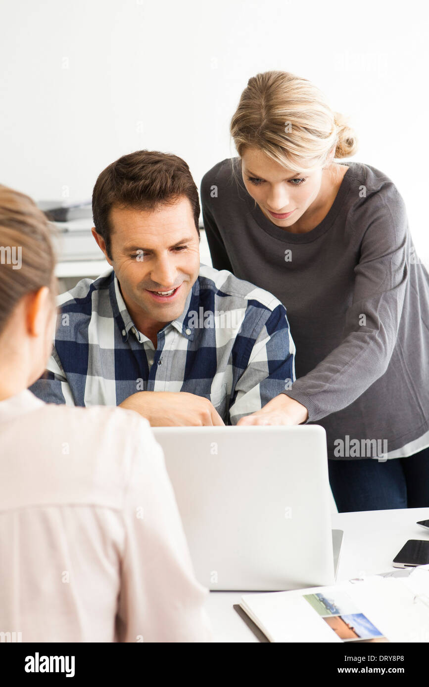Colleagues gathered around laptop collaborating on work project Stock Photo
