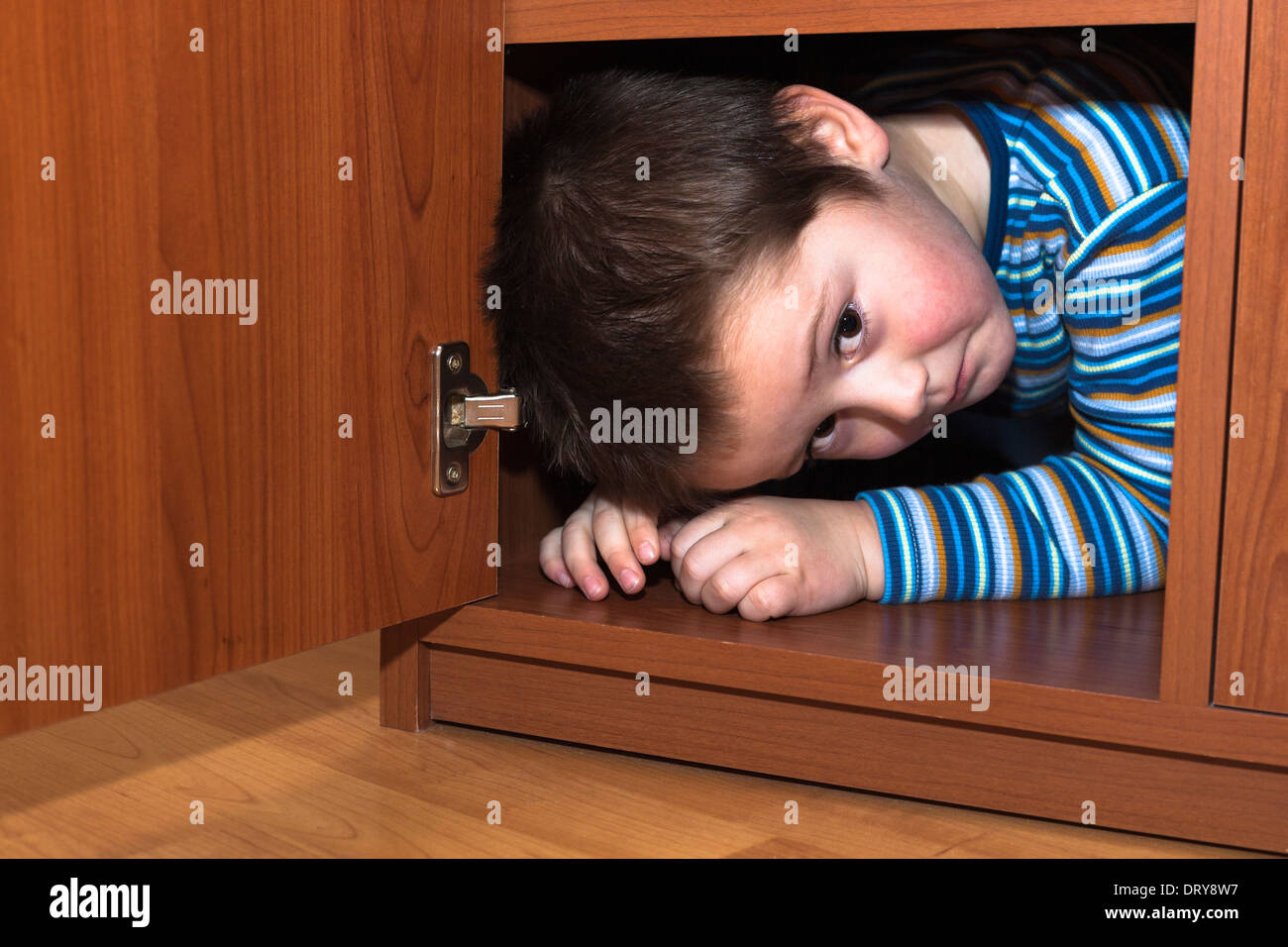 Scared child boy hiding in wardrobe Stock Photo