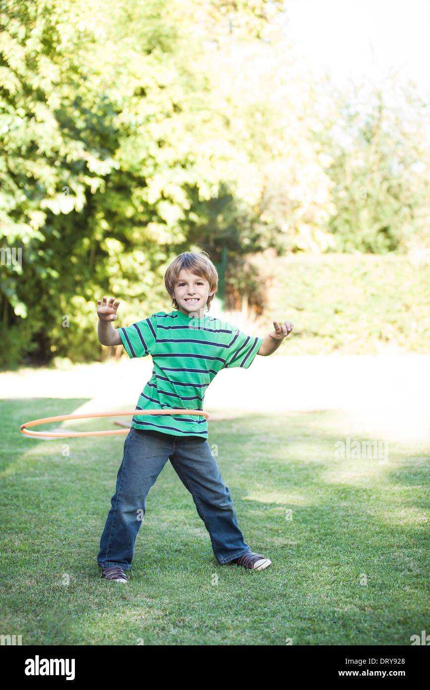 Boy playing with hula hoops in yard Stock Photo