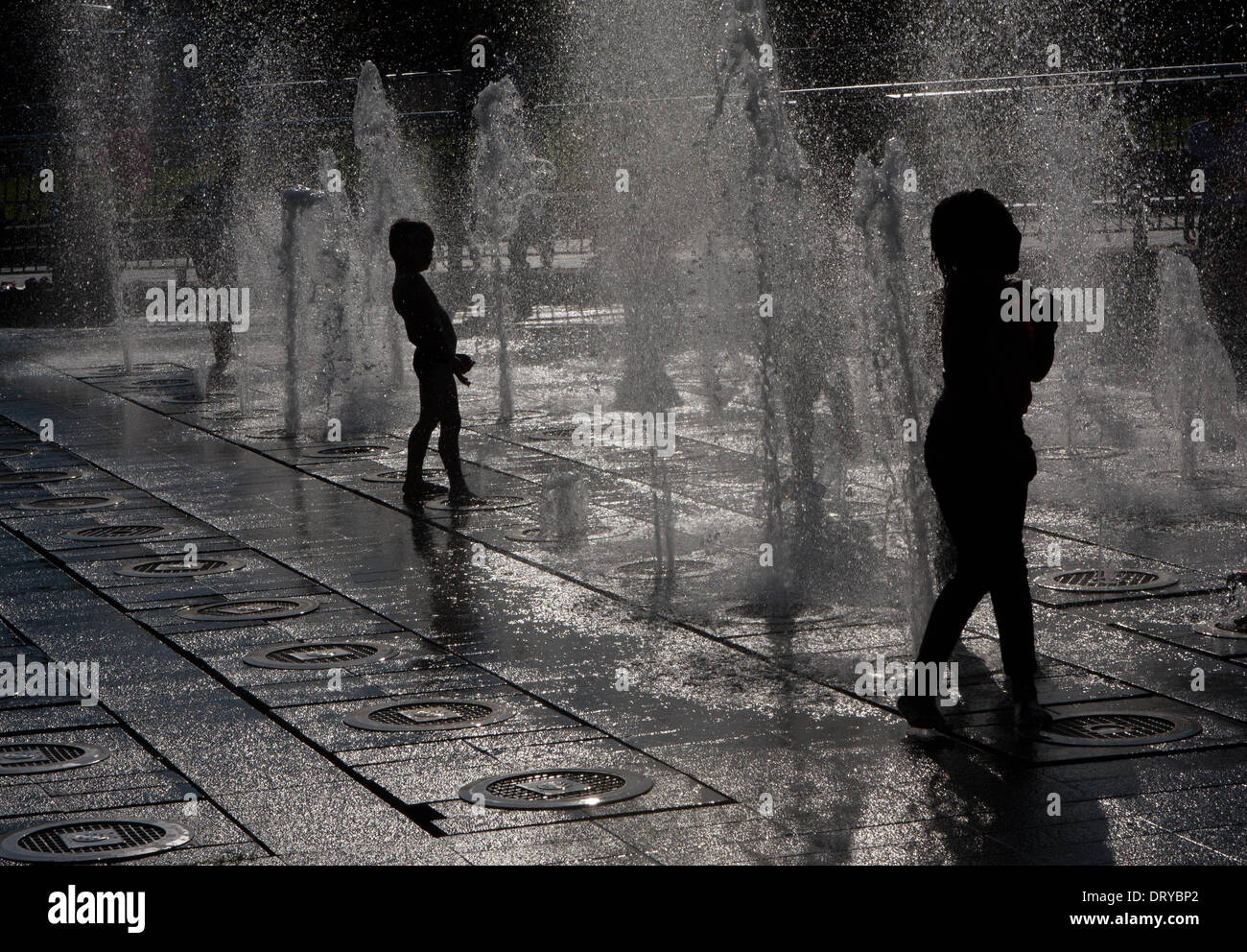Silhouettes of children playing in water fountains Stock Photo - Alamy