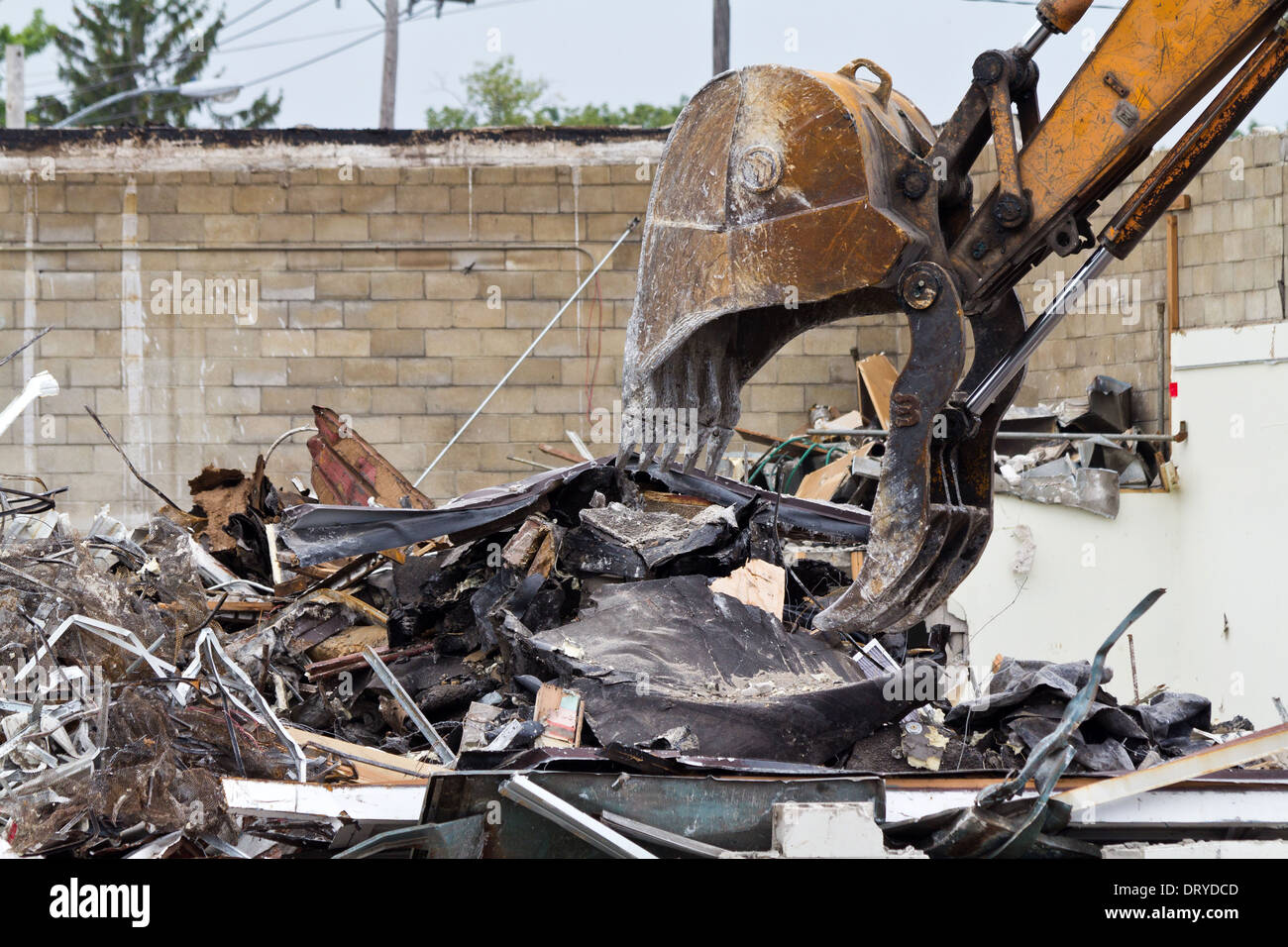 Digger bucked.Demolished a building in the city. Excavator loads rubble from the wall. Rubble ruins wreckage nobody from side hi-res Stock Photo