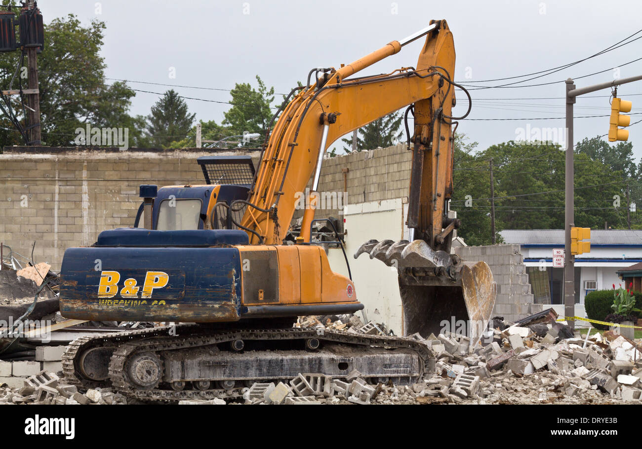 Digger bucked..Demolished building in the city. Digger with backhoe operator demolition old house.Excavator loads rubble from the wall a house hi-res Stock Photo