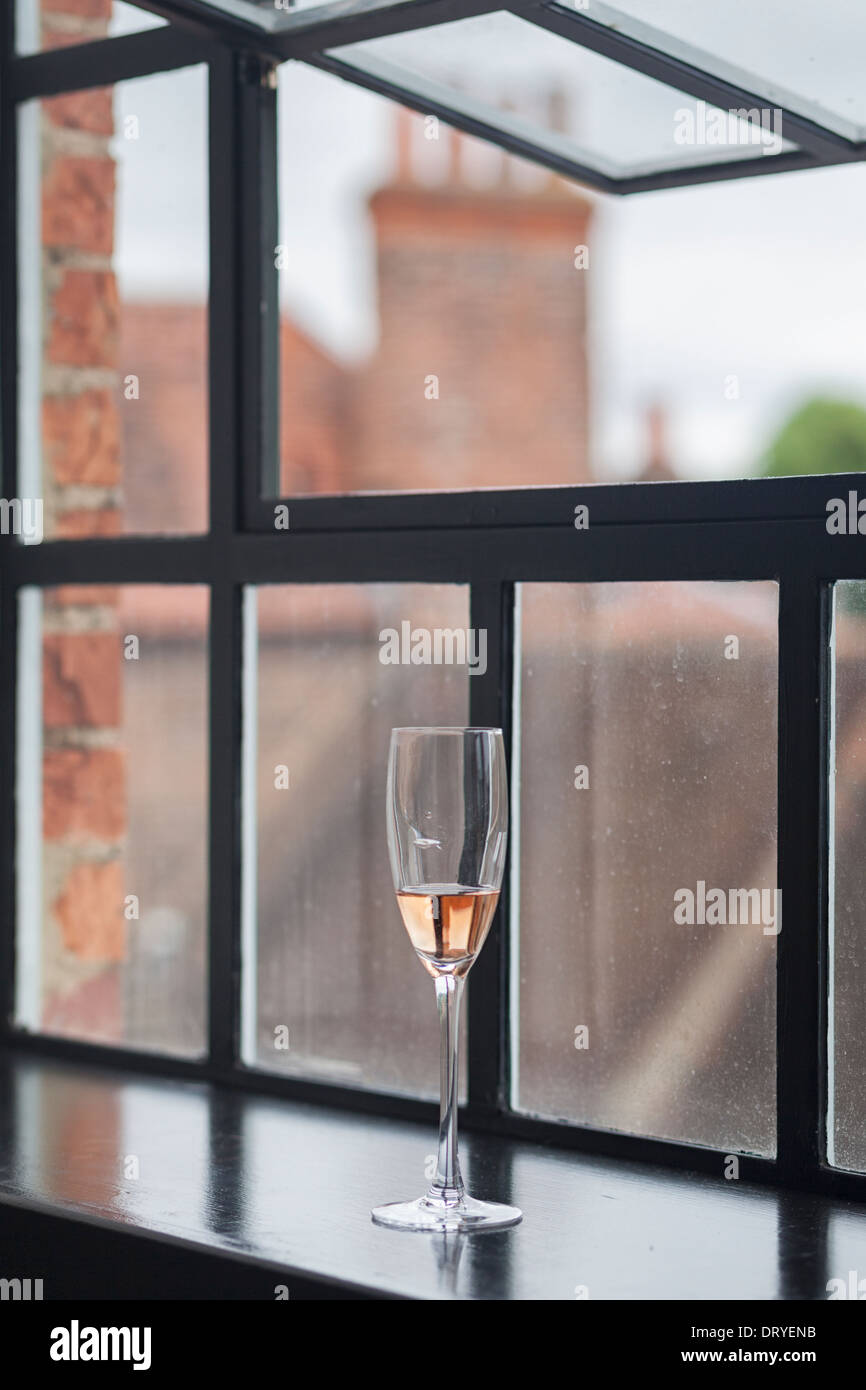 Champagne glass by window sill Stock Photo