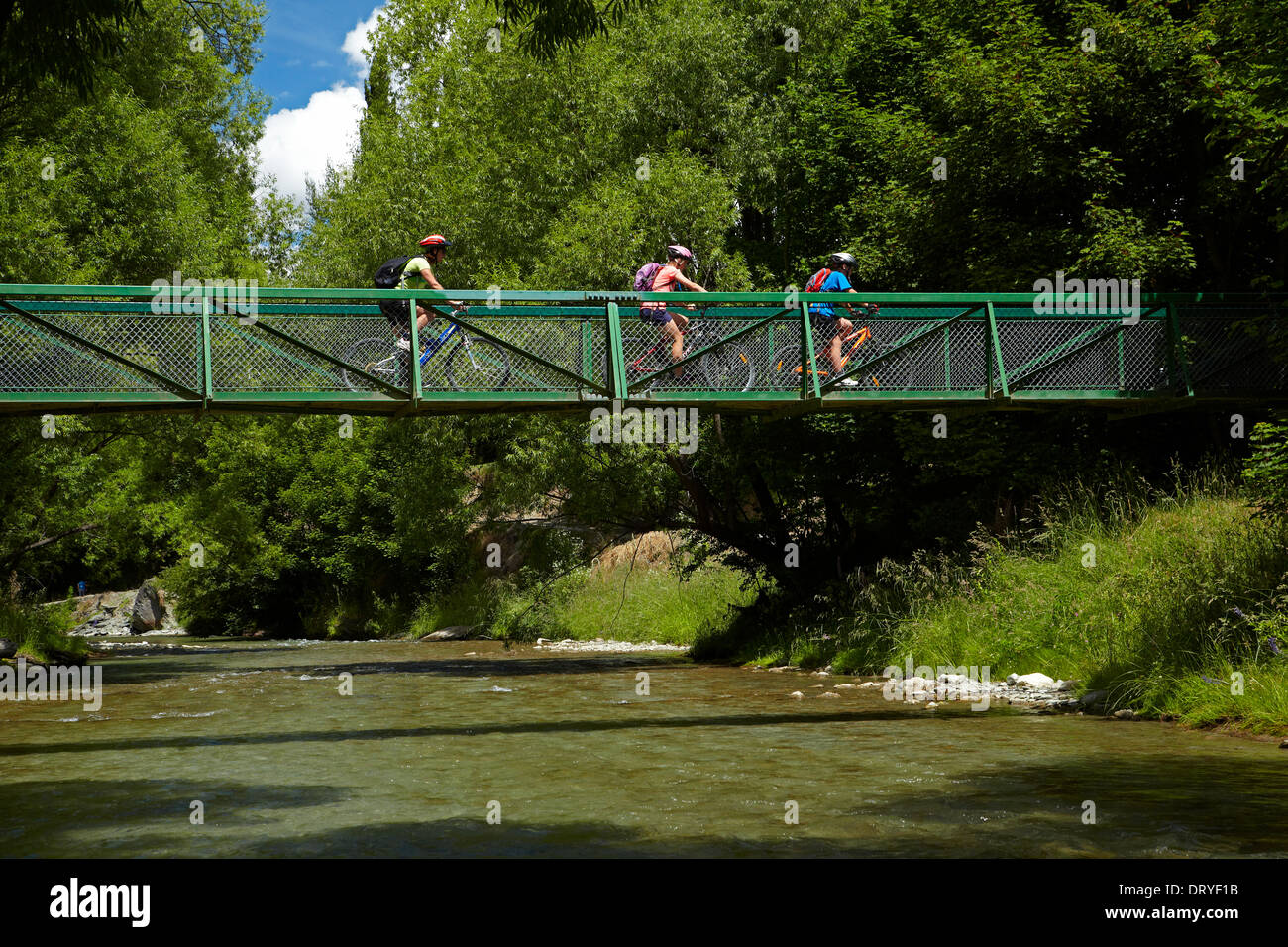 Mountain bikers crossing bridge on Arrow River Bridges Ride, near Arrowtown, Otago, South Island, New Zealand Stock Photo