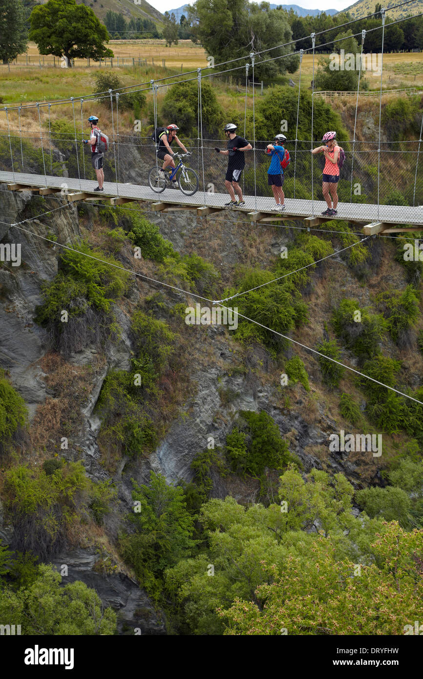 Mountain bikers above the Arrow River on Edgar suspension bridge, Arrow River Bridges Ride, Otago, South Island, New Zealand Stock Photo