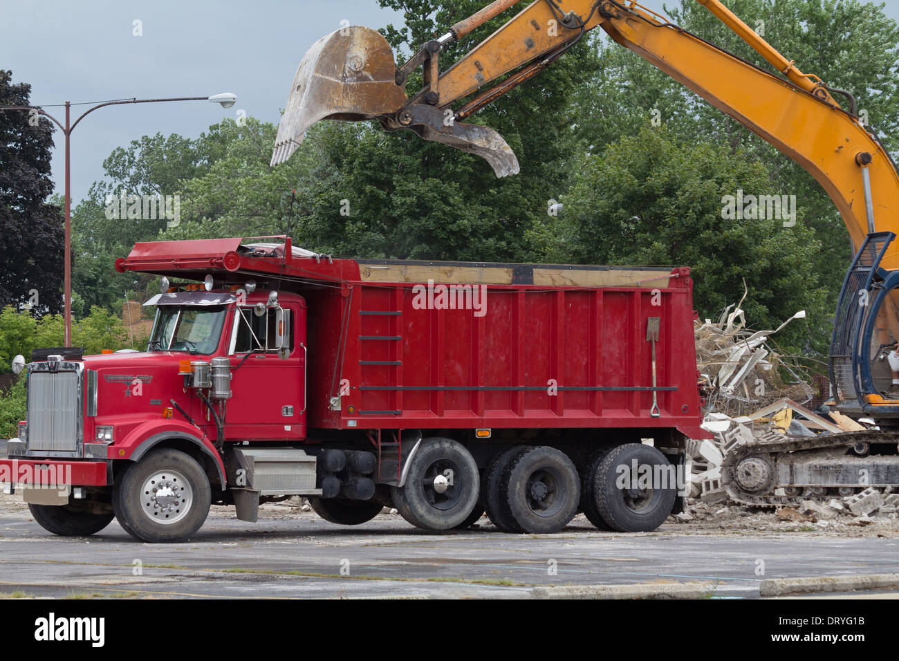Closeup of Backhoe loader.Demolished building.Digger with a driver demolition Excavator loads rubble on drump truck horizontal  in USA US hi-res Stock Photo
