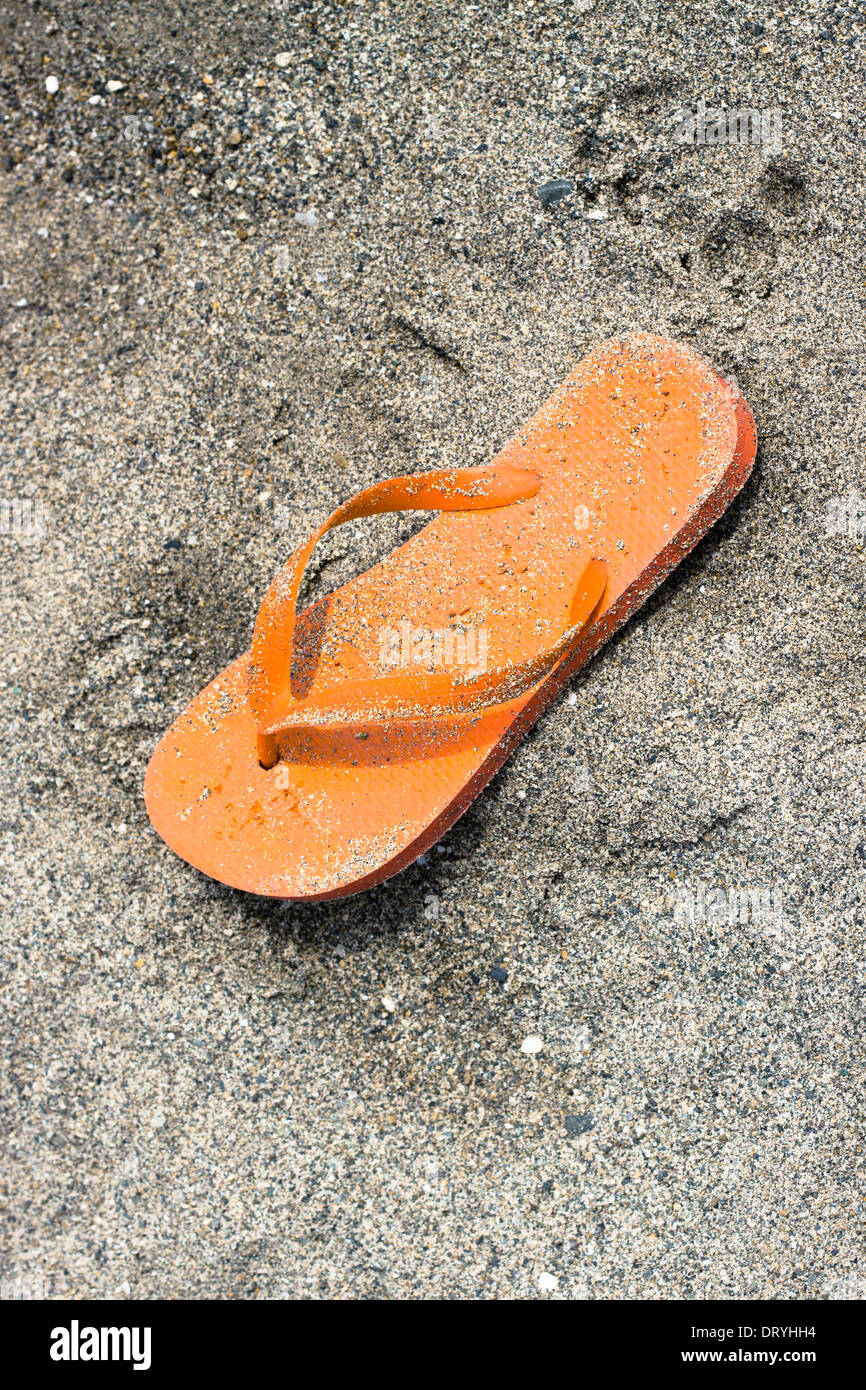 Orange flip-flop on sandy beach. Stock Photo
