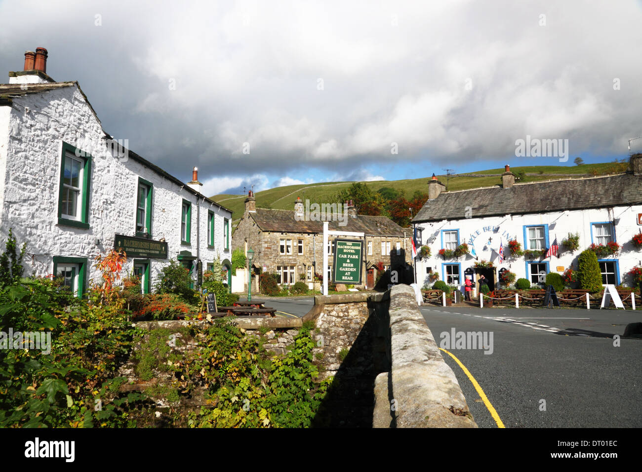 A village with whitewashed stone cottages and a 'Blue Bell' and 'Racehorses Hotel' 'pub signs. Stock Photo