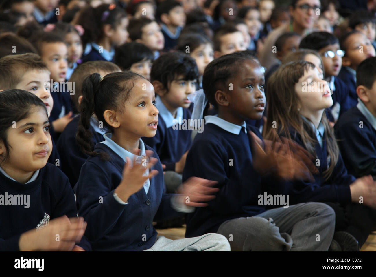 Children at a school assembly singing, clapping and performing actions Stock Photo