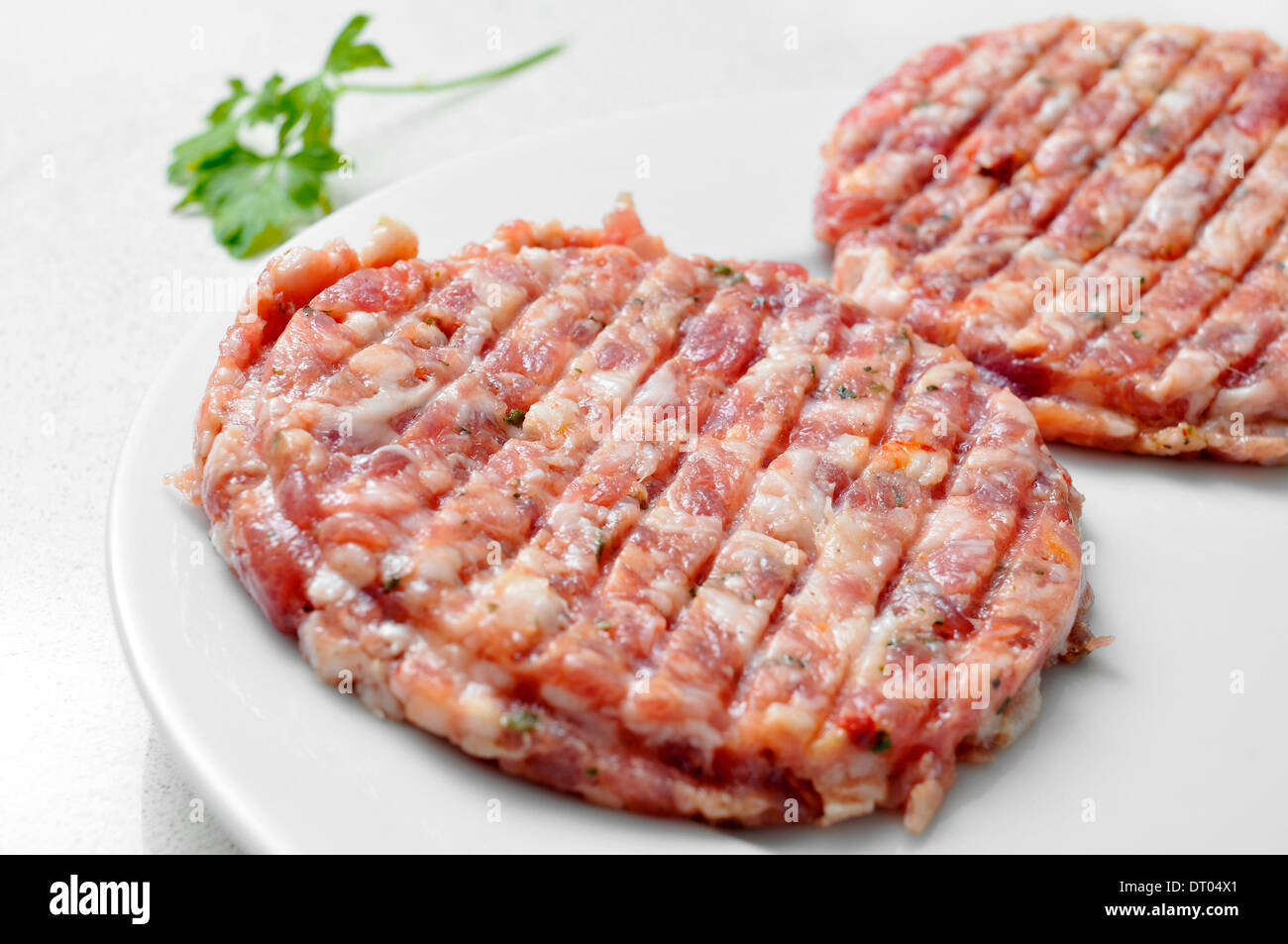 closeup of some raw spiced burgers in a plate Stock Photo