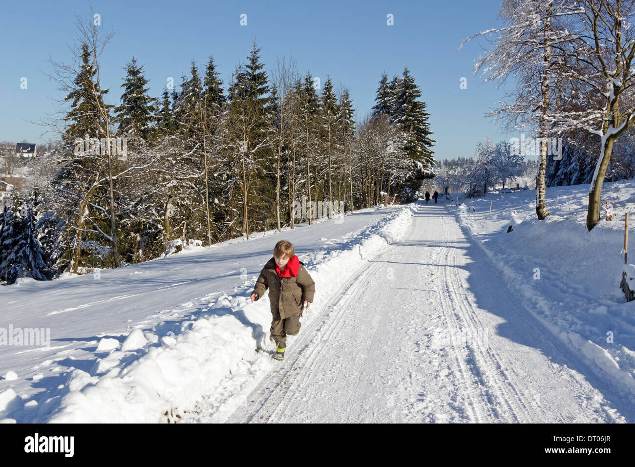 young boy running along a snow coverd road at Neuastenberg near Winterberg, Sauerland, Northrhine Westfalia, Germany Stock Photo