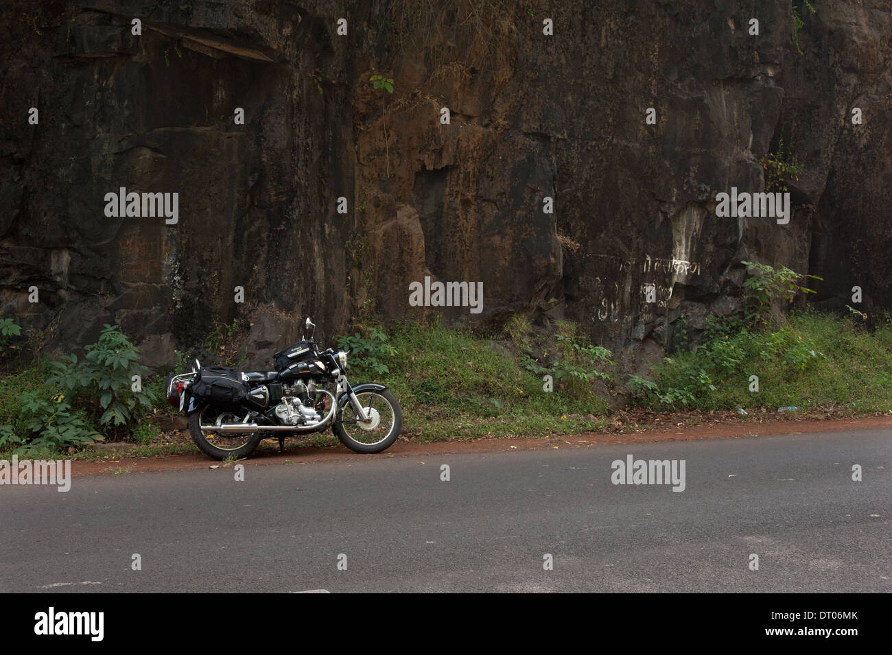 Royal Enfield on NH 17 Mumbai Goa road against rock cliff. Stock Photo