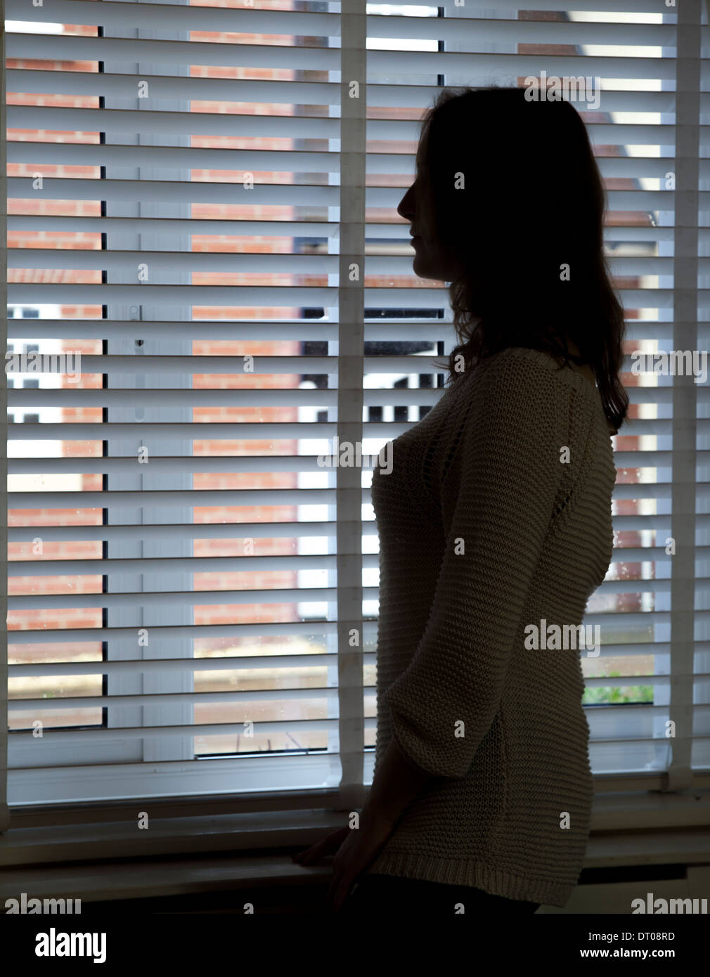Silhouette of woman standing by a window. Profile/side view. Stock Photo