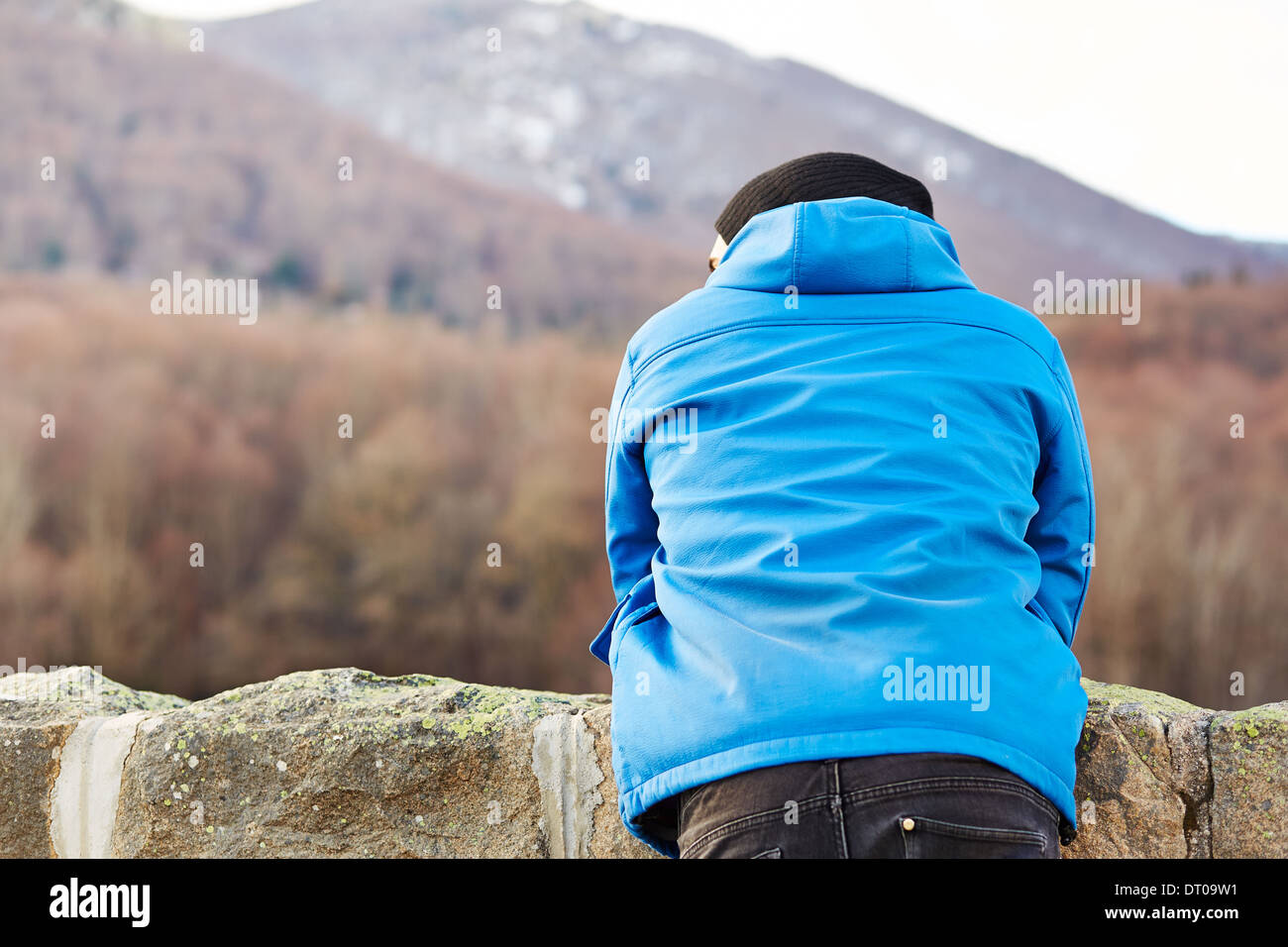 Young man on blue jacket staring at winter landscape Stock Photo
