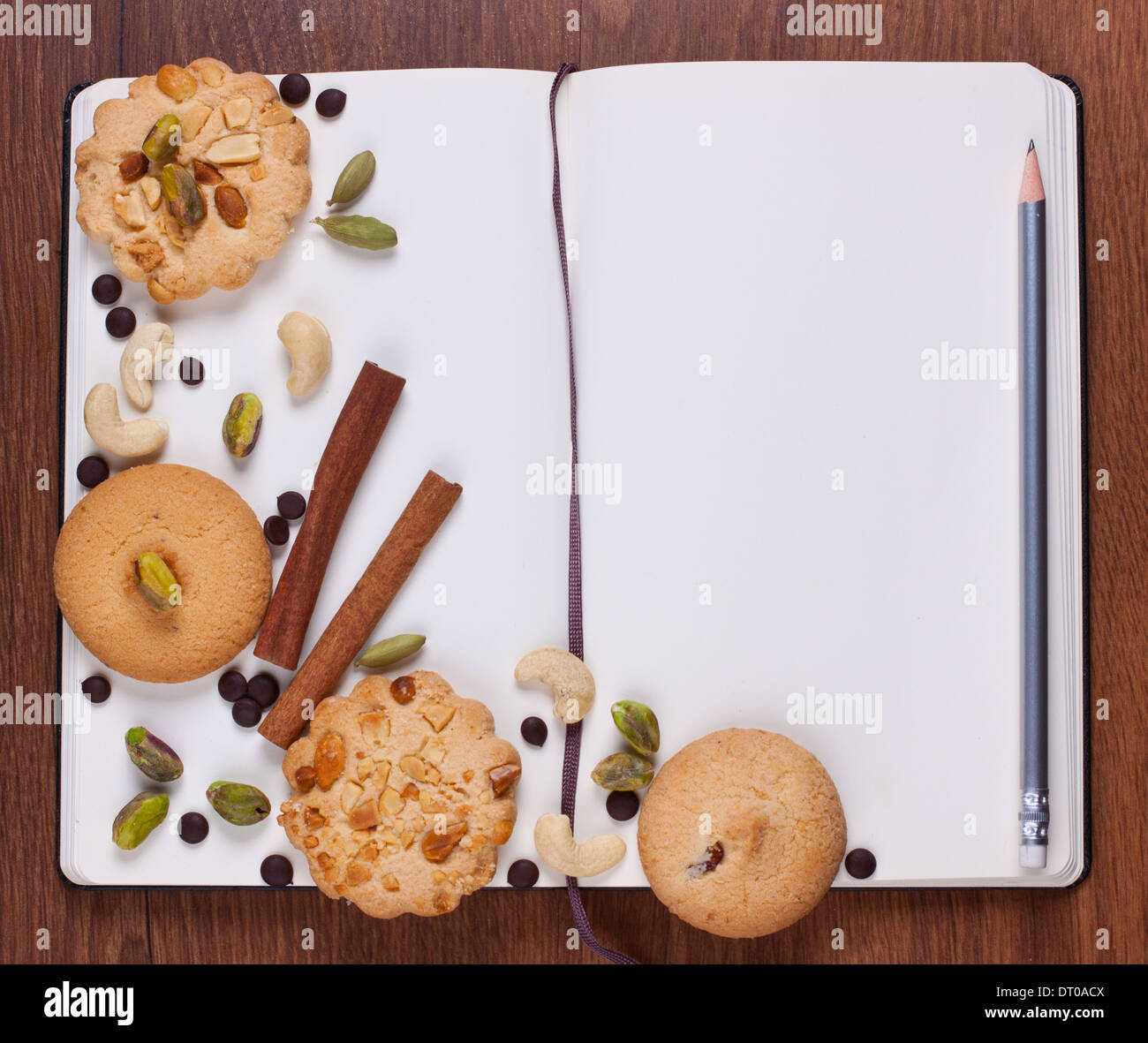 Open blank notebook with assorted cookies and nuts on it Stock Photo