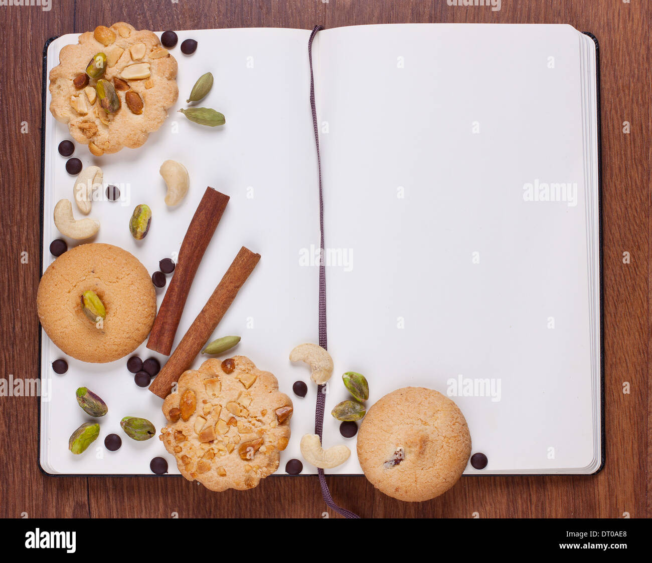 Open notebook with biscuits and nuts on it Stock Photo