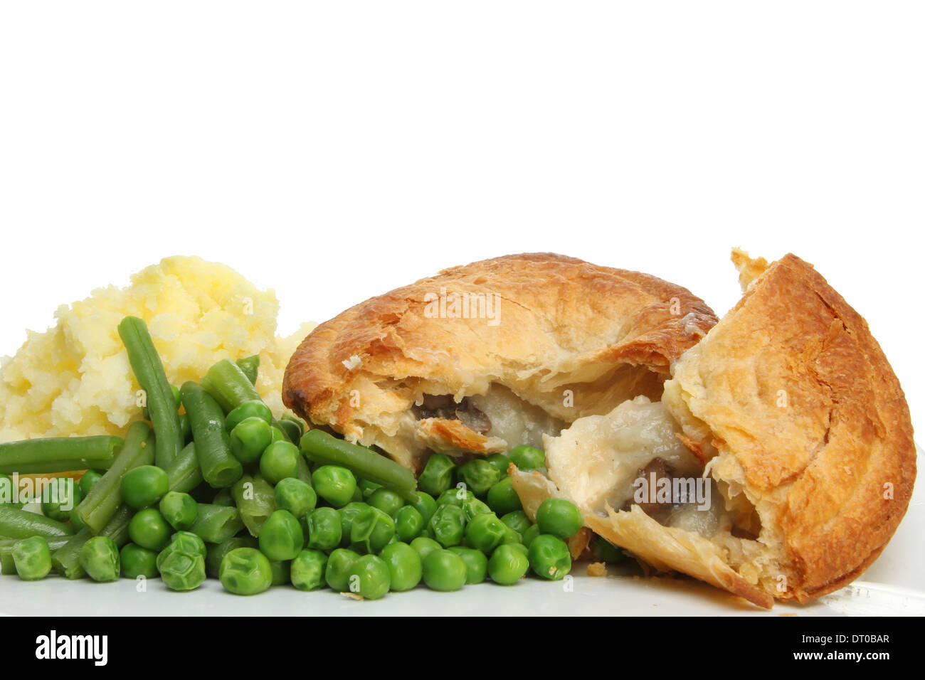 Closeup of a chicken and mushroom pie with mashed potato, green beans and peas against a white background Stock Photo