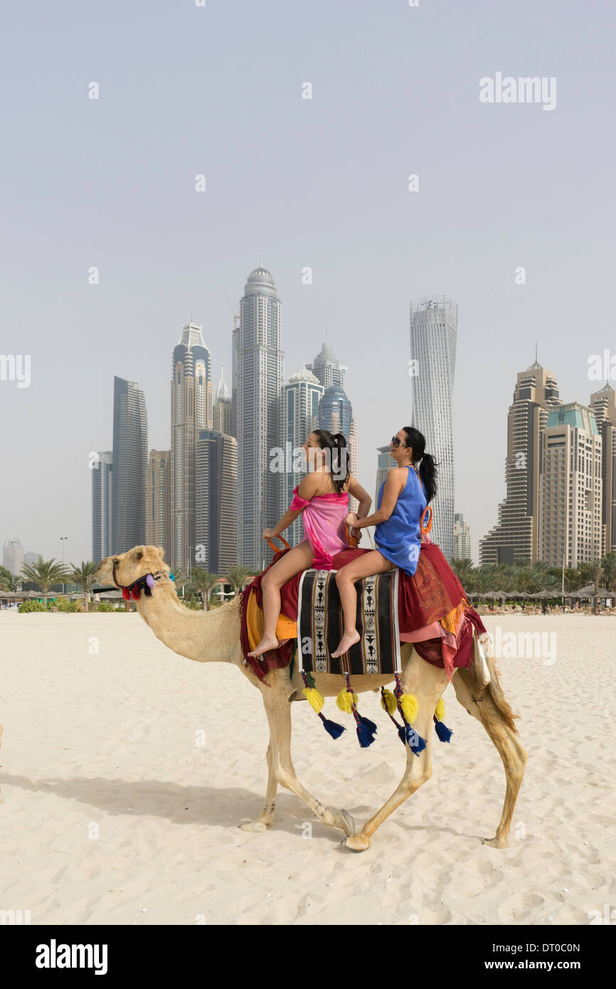 Tourists taking a camel ride on beach at Marina district of New Dubai in United Arab Emirates Stock Photo