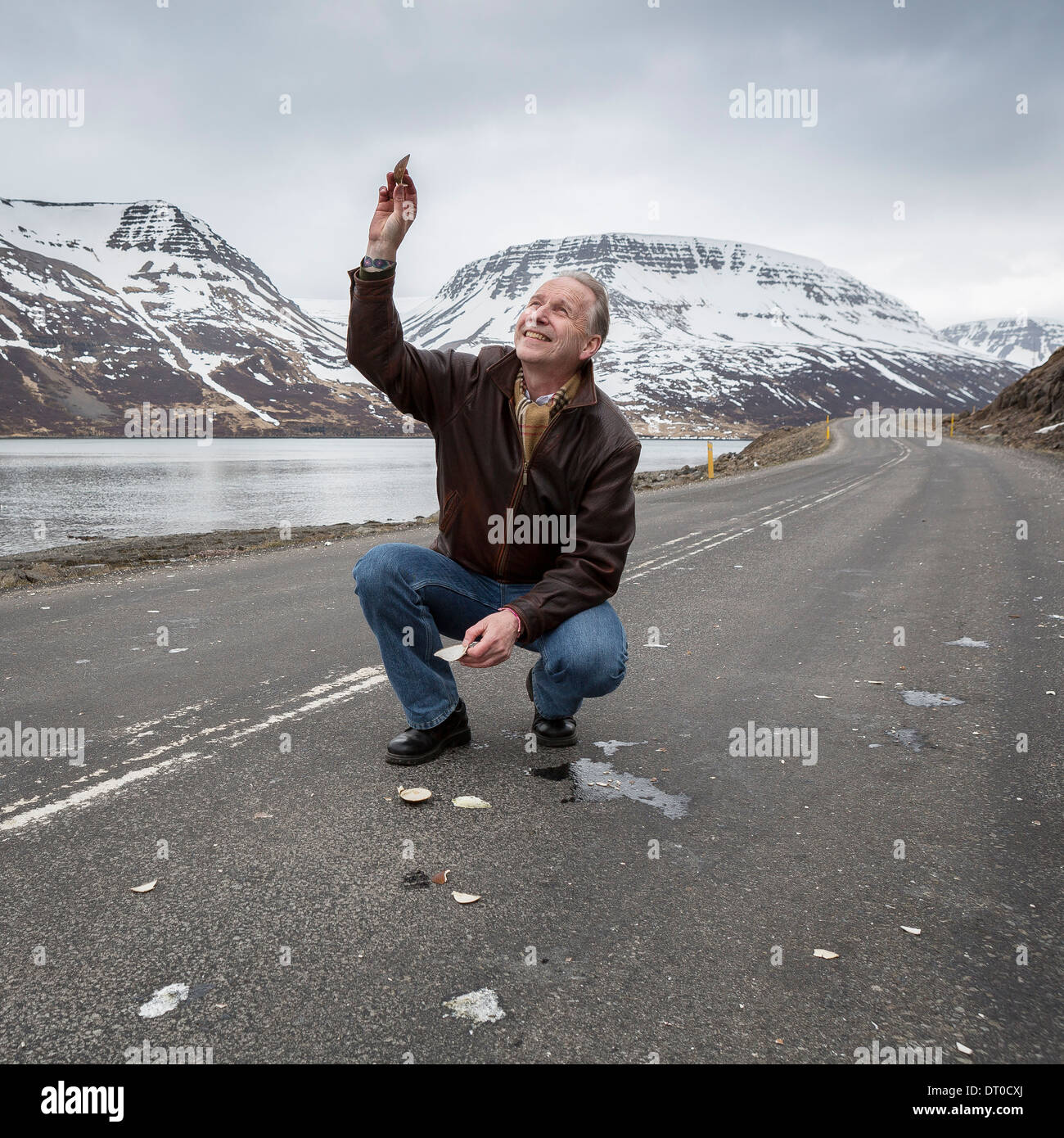 Geophysicist in the road trying to get the attention of the birds flying above,  Sugandafjordur, Western, Iceland Stock Photo