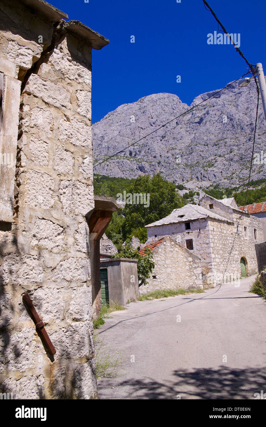 Typical stone houses in old village of Tucepi below towering mountains