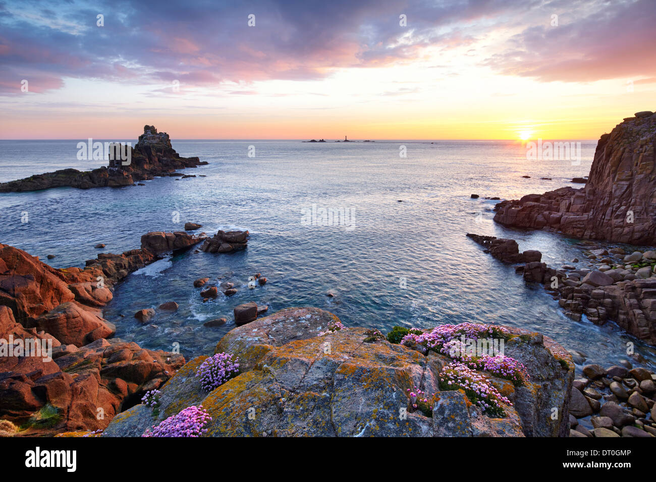 The sun setting at Land's End with thrift clinging to the rocks. Stock Photo