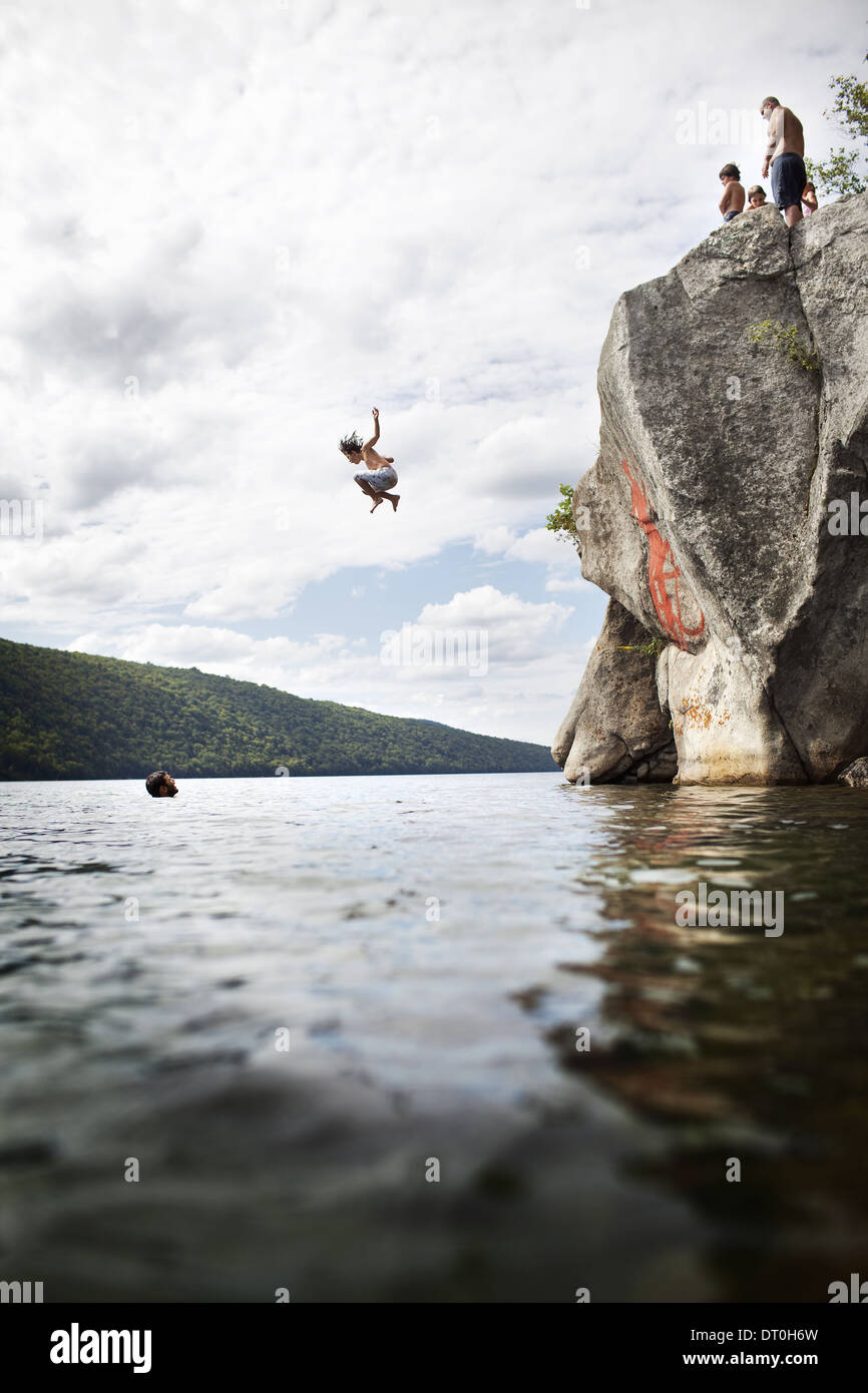 Massachusetts USA group of young people jumping from cliff lake Stock Photo