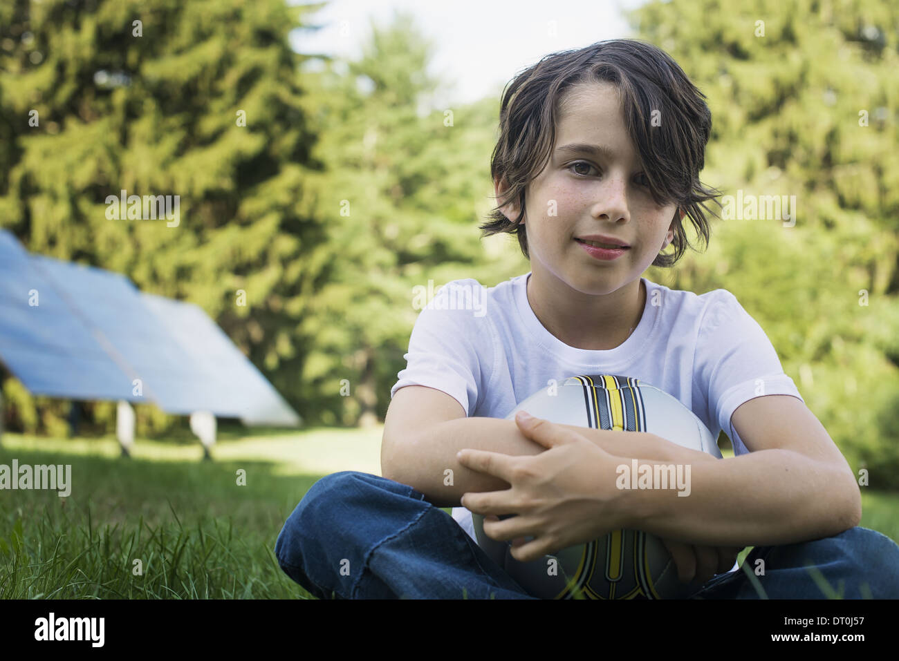 Woodstock New York USA boy holding football sitting on grass Solar panels Stock Photo