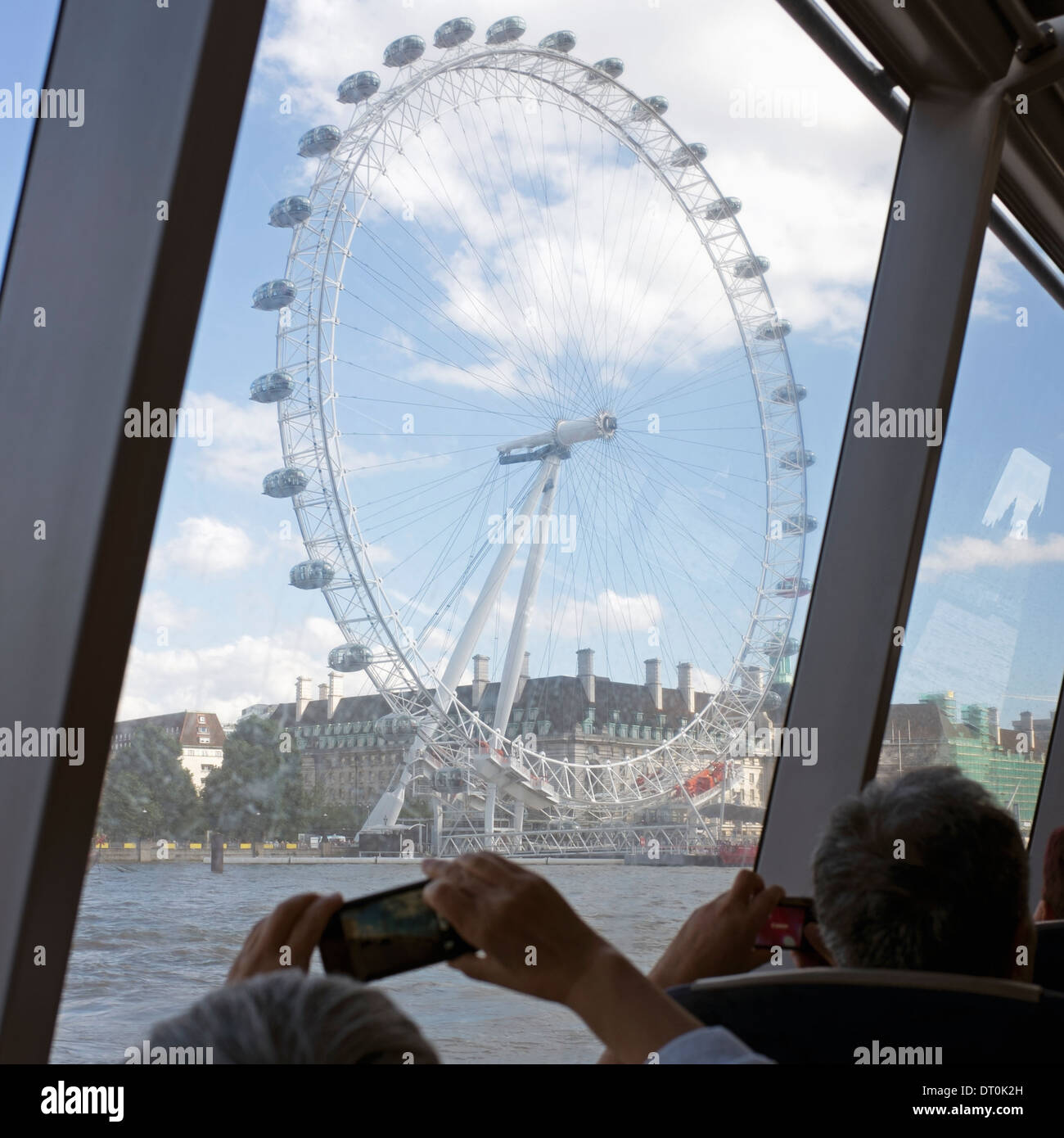Tourists photographing The London Eye from the window of the river boat cruise. Stock Photo