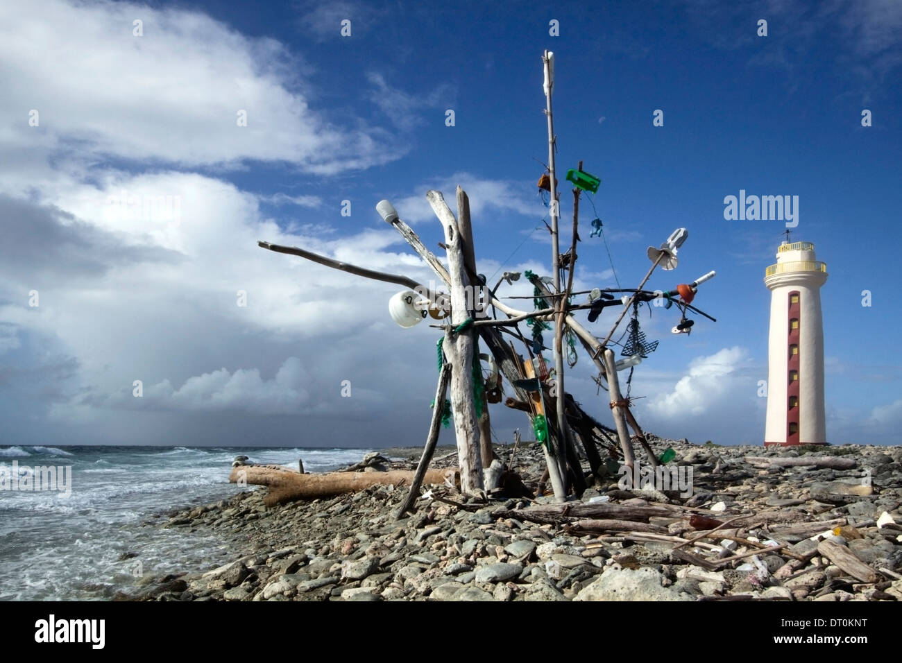 Beach art made from jetsam and flotsam in Bonaire. Willenstoren lighthouse seen in background Stock Photo