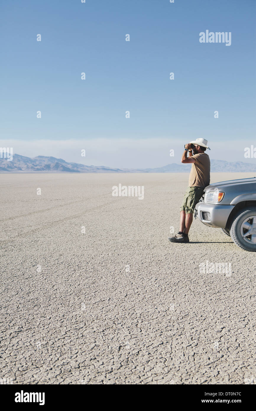 Black Rock Desert Nevada USA man leaning against truck using binoculars Stock Photo
