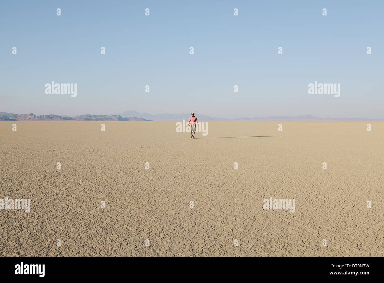 Black Rock Desert Nevada USA Man walking across flat desert landscape Stock Photo
