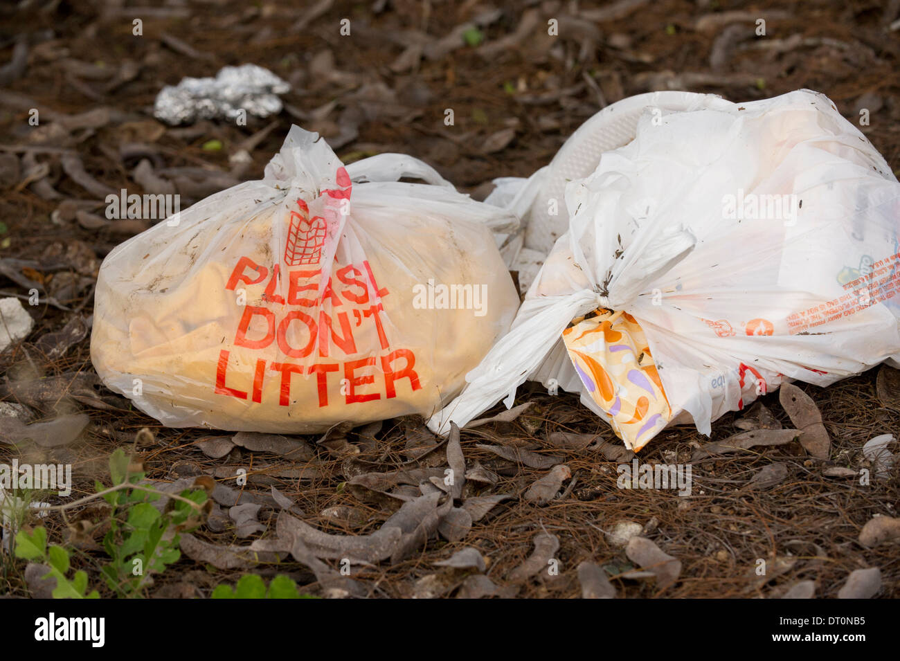 'Please don't litter' plastic bags filled with trash on ground at a rest stop in rural south Texas. Stock Photo