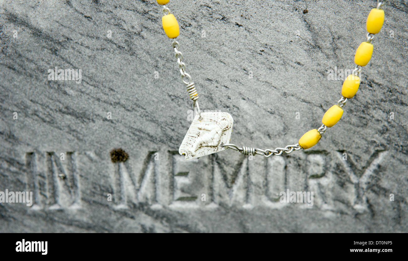 A rosary hangs on an old stone grave Stock Photo