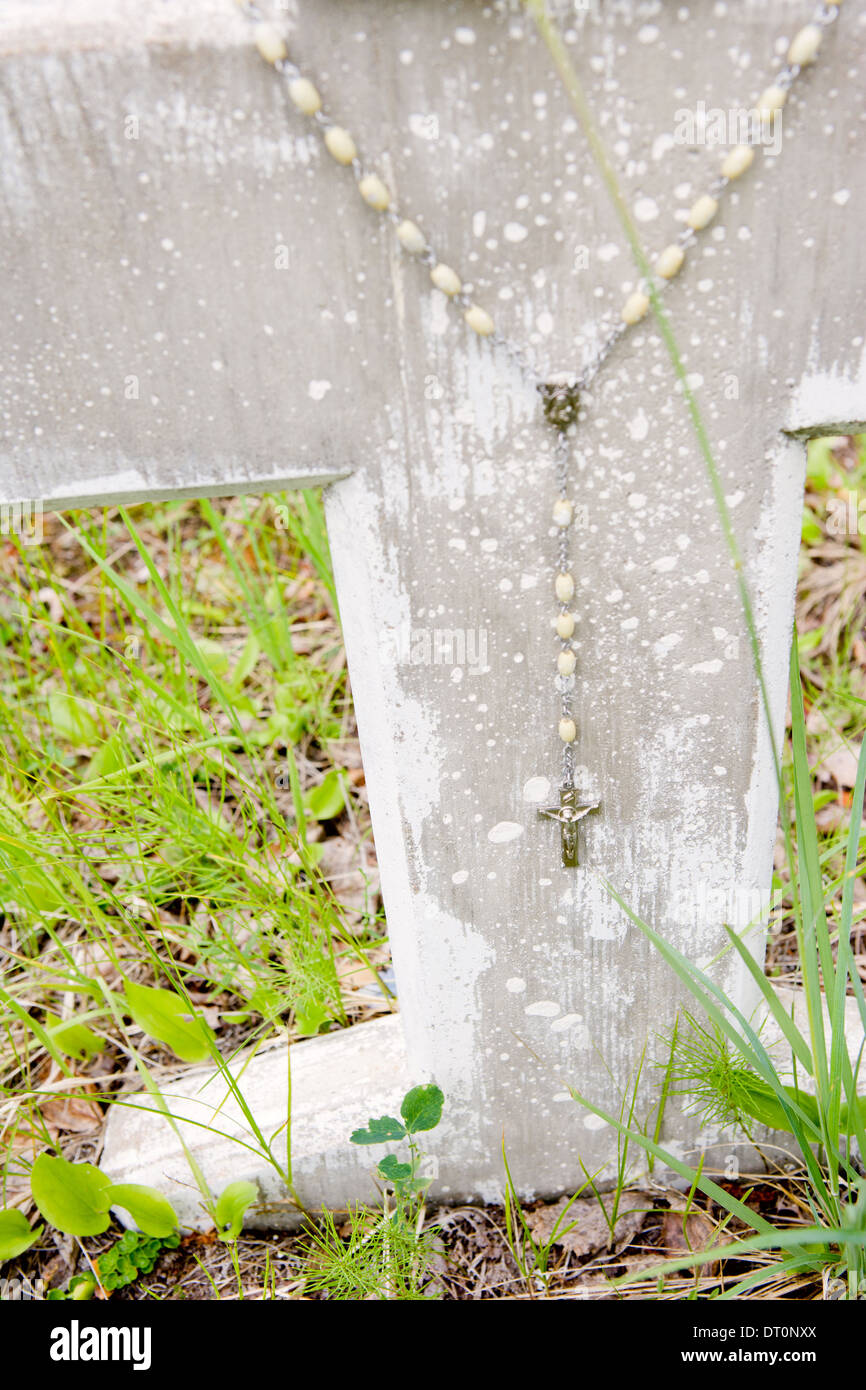 A rosary hangs on an old stone grave Stock Photo