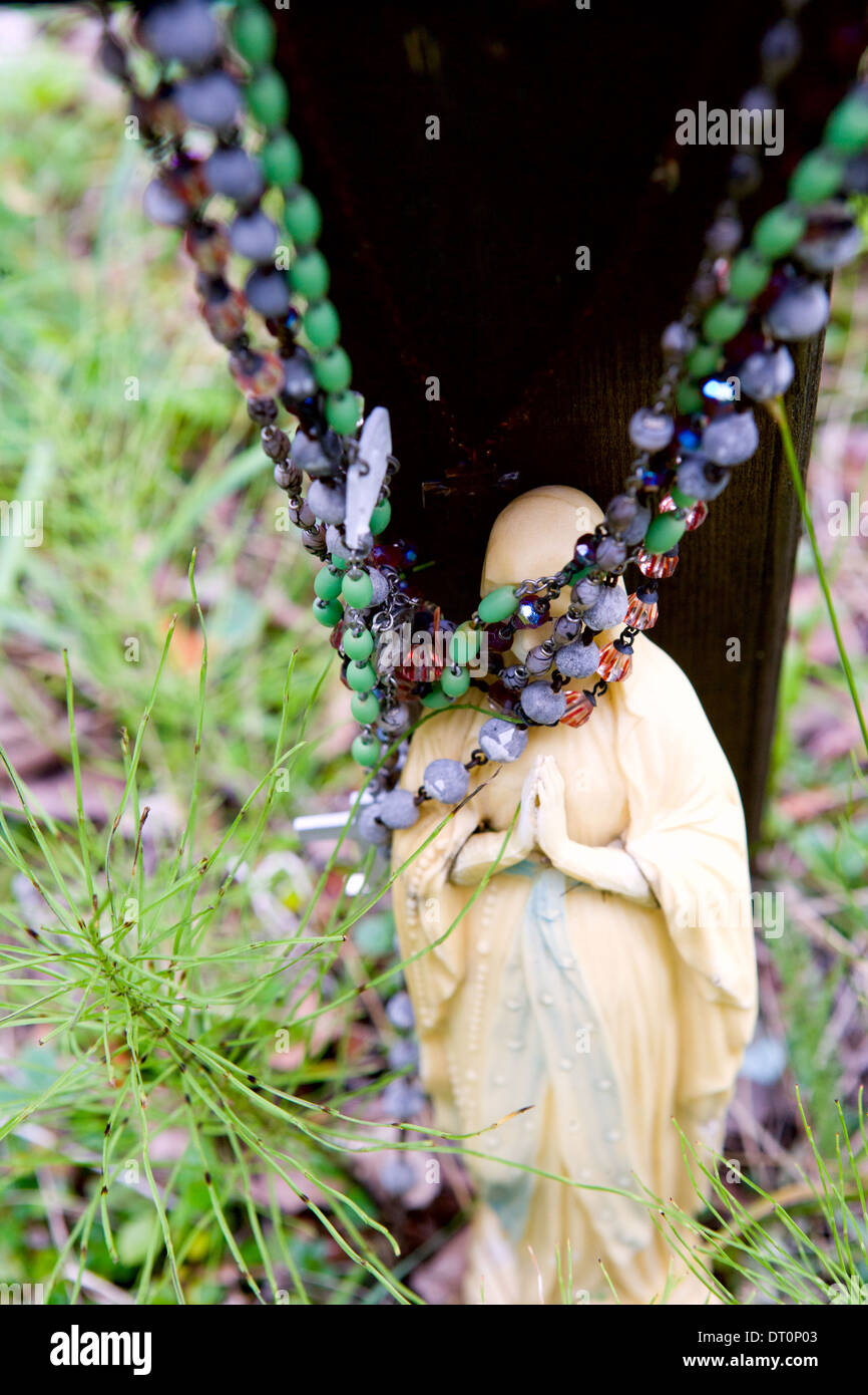 Rosaries cover the Virgin Mary's face in a graveyard Stock Photo