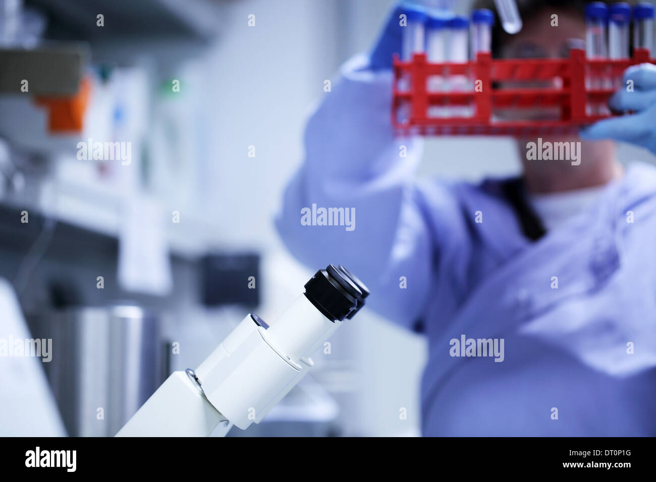 ocular of a microscope and a scientist with blue lab coat Caucasian woman working Stock Photo