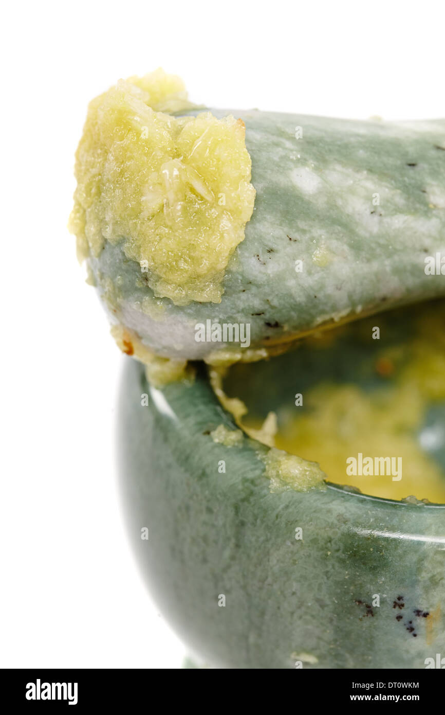 Closeup of crushed garlic in the mortar and on the pestle, isolated