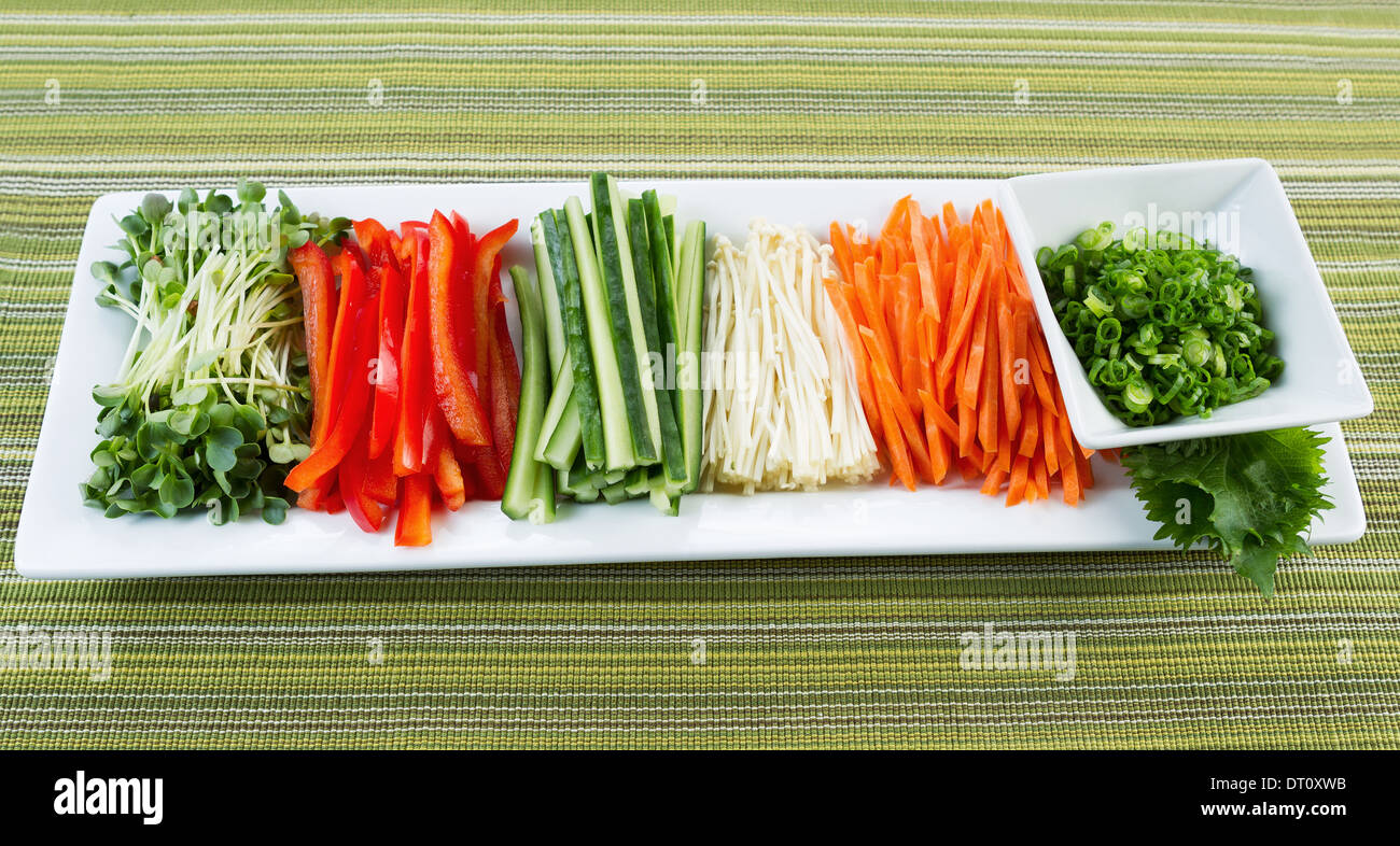 Horizontal photo of fresh sushi ingredients place in long plate with textured table cloth underneath Stock Photo