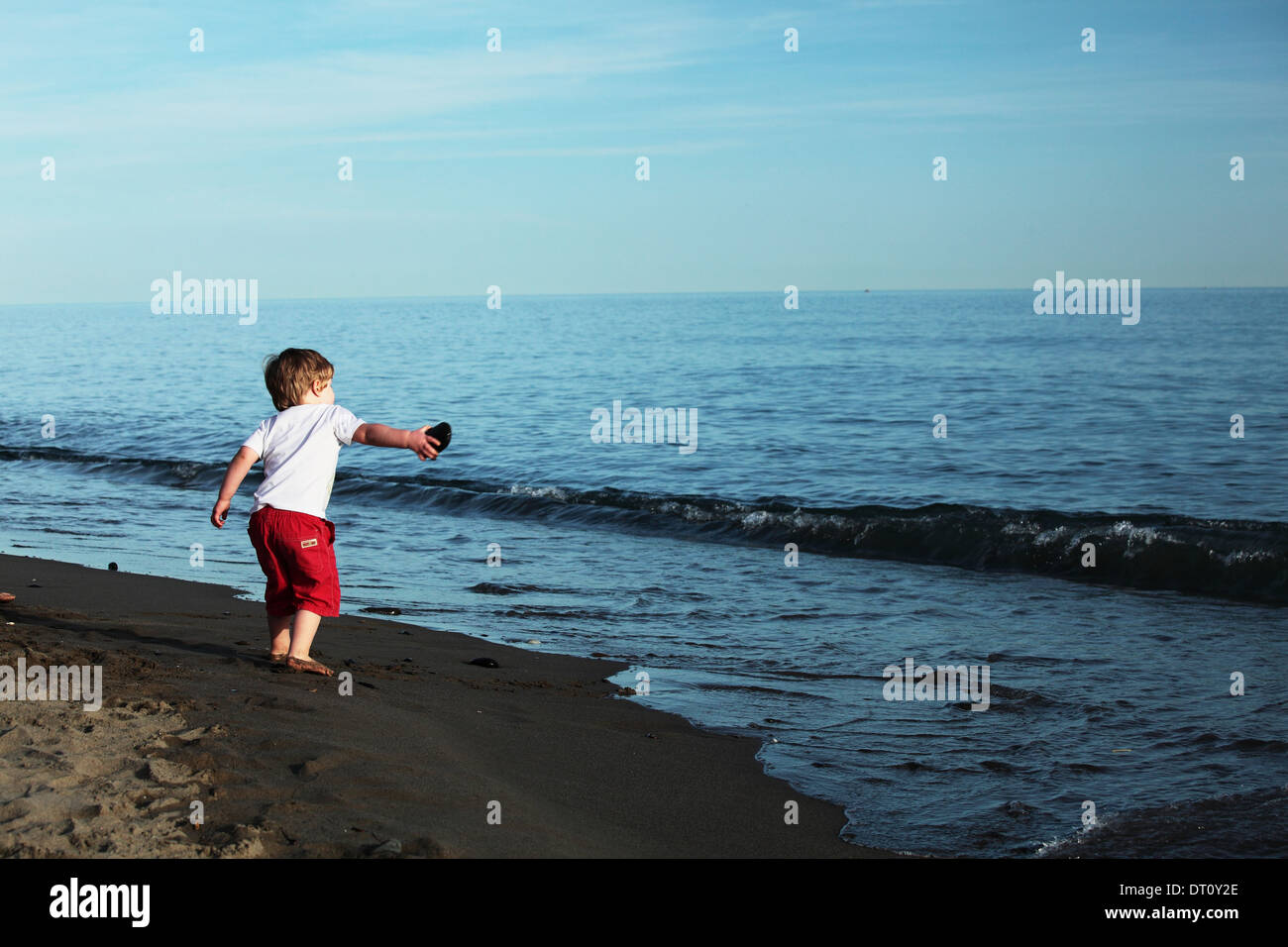 Young boy throwing a stone into the sea Stock Photo Alamy
