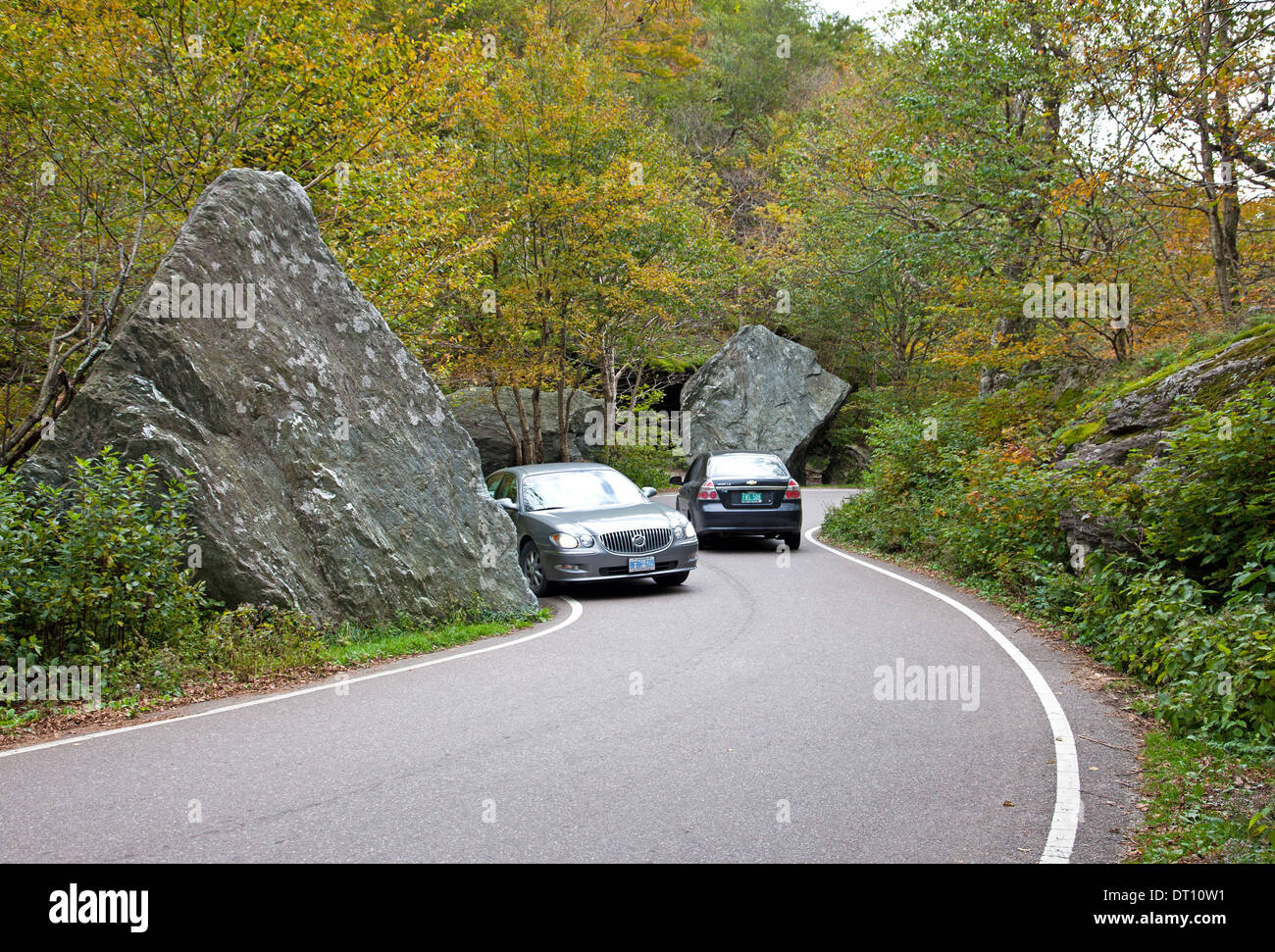 Two cars approach top of Smugglers' Notch (VT 108) through graceful trees on west side of road in Vermont's Green Mountains. Stock Photo