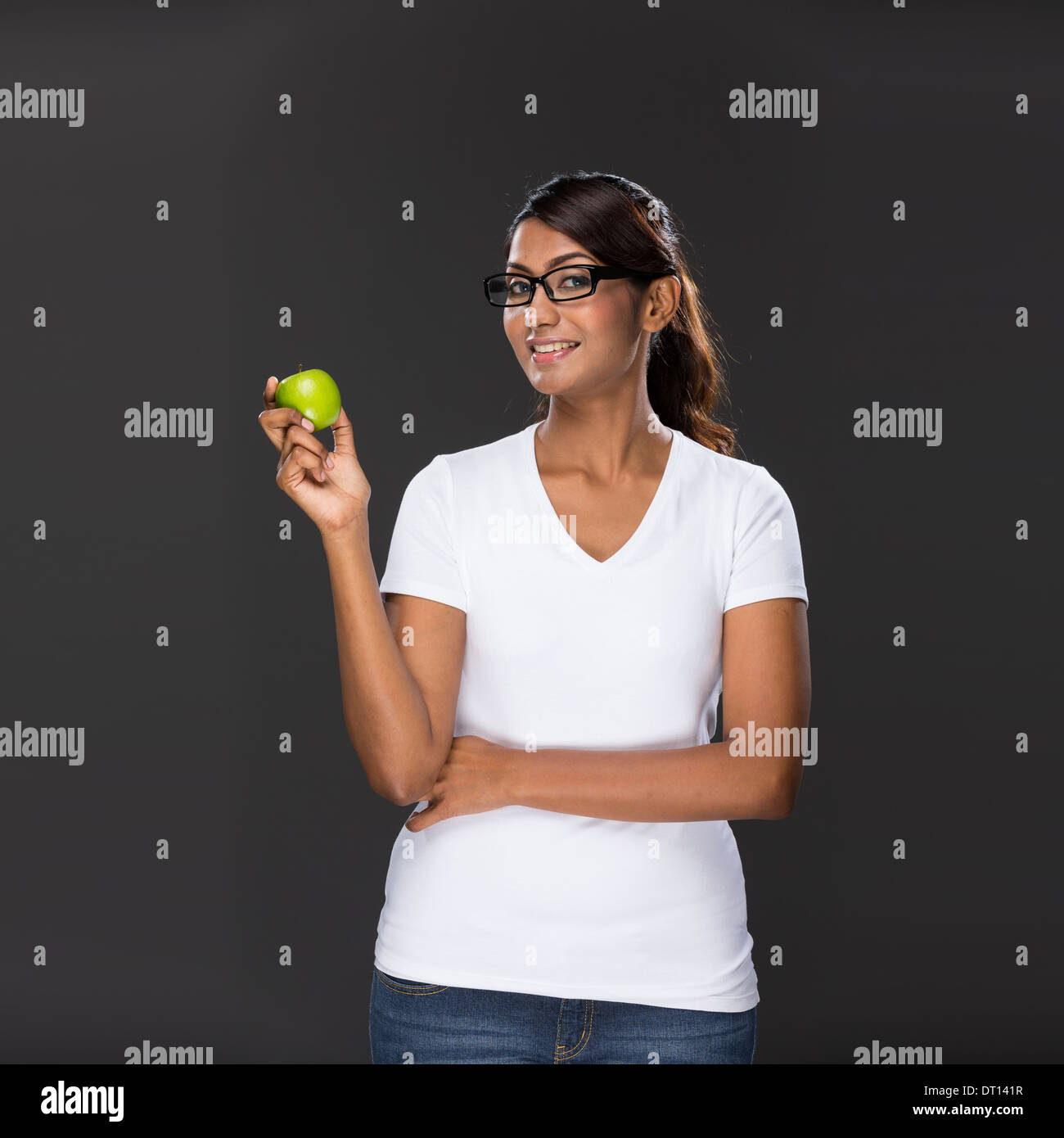 Happy Asian woman standing in front of a dark chalkboard. The chalk board is blank waiting for a message. Stock Photo