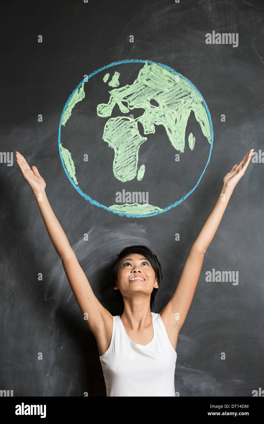 Asian Business woman or teacher with chalk globe drawn on blackboard. Stock Photo