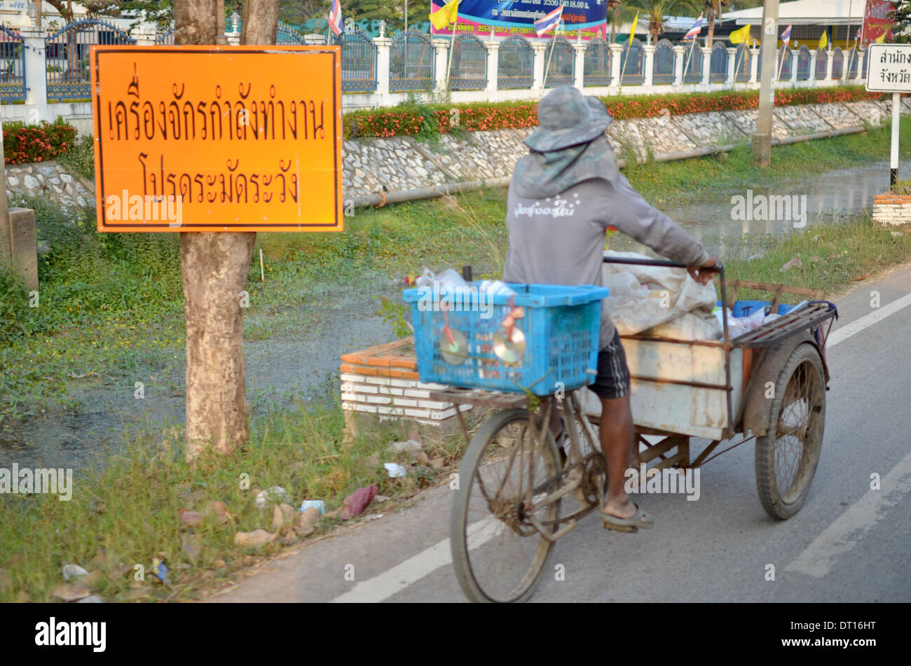 Thai man riding rickshaw on main road, with Thai road sign, Ko Lantah, Thailand Stock Photo