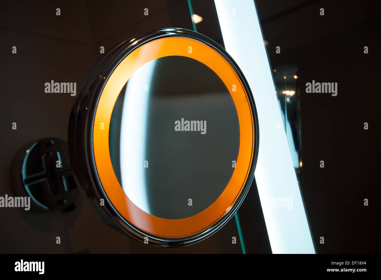 Round mirror with orange light in the bathroom Stock Photo