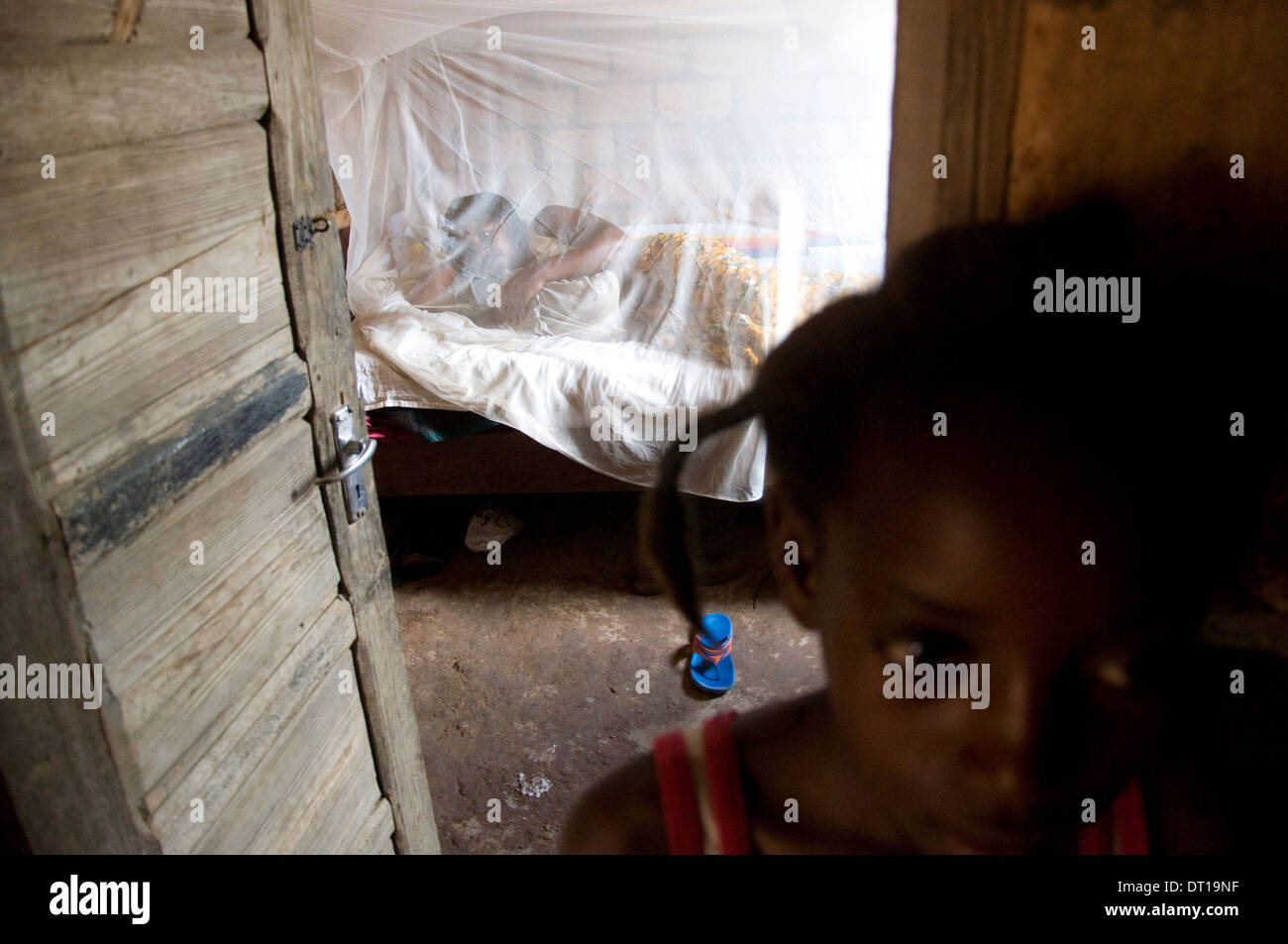 mother and child under mosquito net with child standing by Stock Photo
