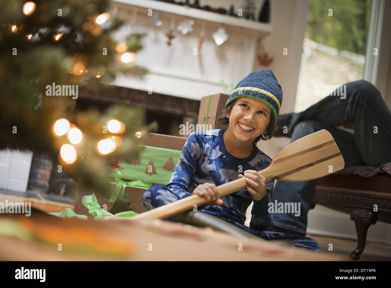 Woodstock New York USA boy by Christmas tree unwrapping gift wooden oar Stock Photo