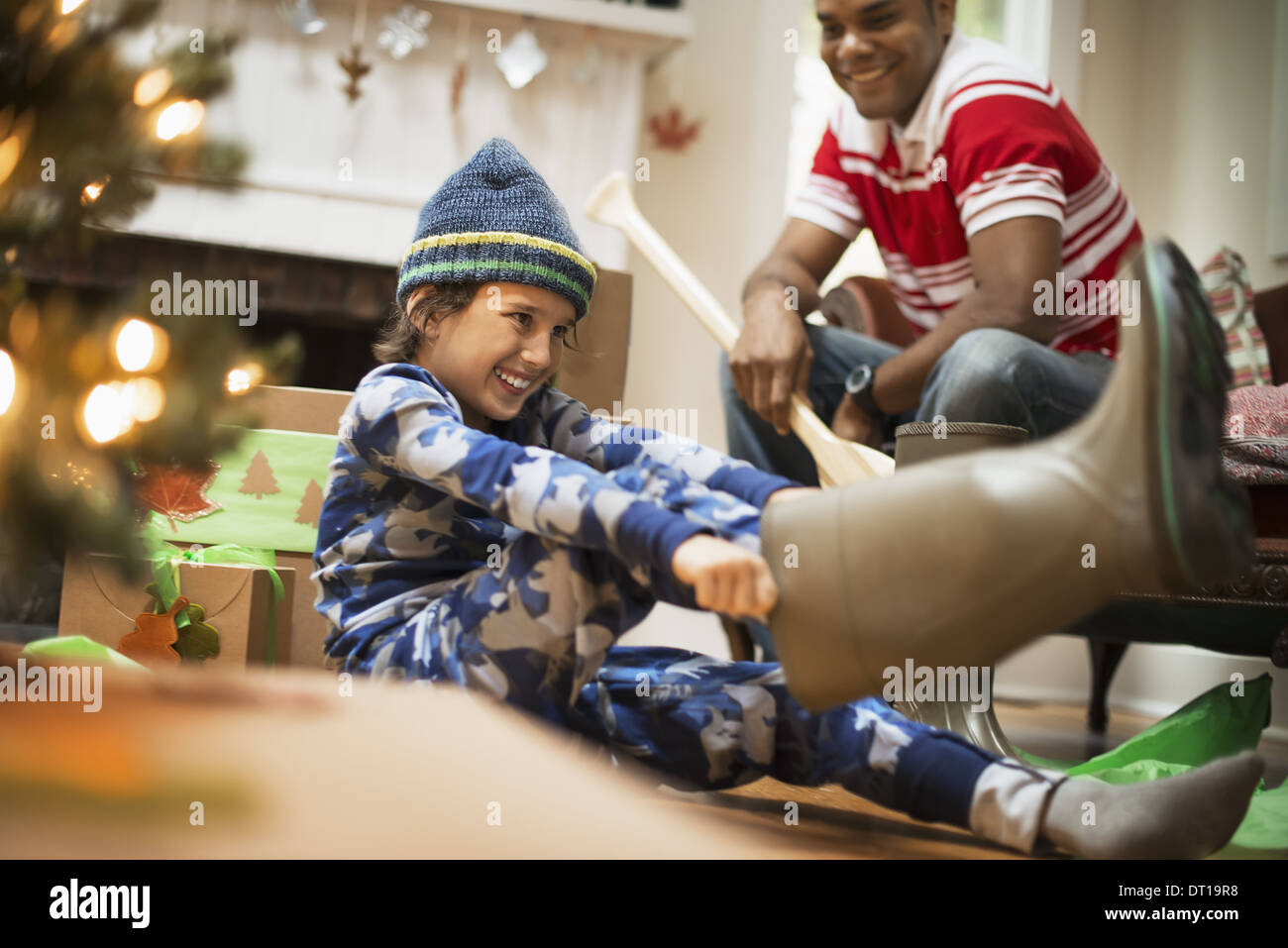 Woodstock New York USA boy by Christmas tree unwraps muck boots Stock Photo