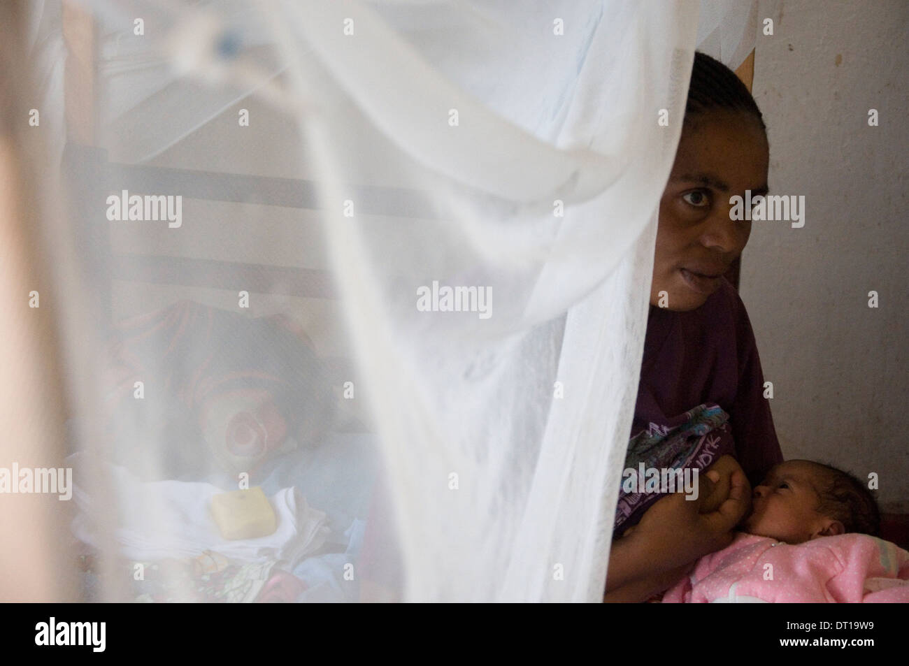 mother and new born child under mosquito net Stock Photo