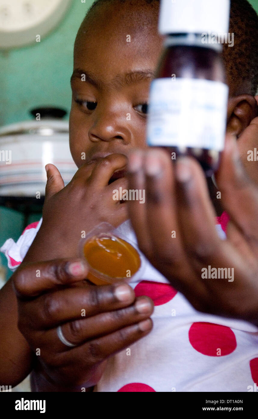 A SPOON FULL OF JAM HELPS THE MEDICINE GO DOWN. Baby 'Peanut' a once premature baby living with her Aunt, gets messy with Stock Photo