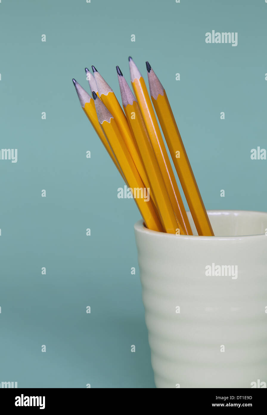 Sharpened pencils in cup on blue background Stock Photo